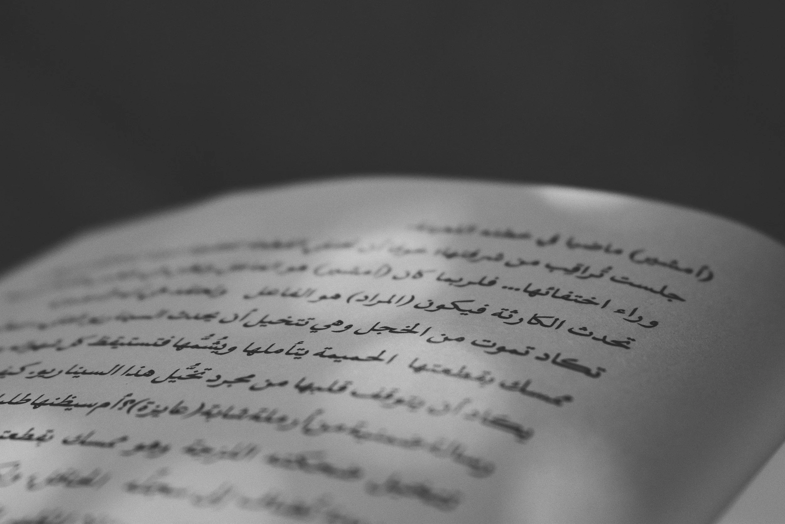 Close-up of a handwritten letter in Arabic on lined paper with a dark background.