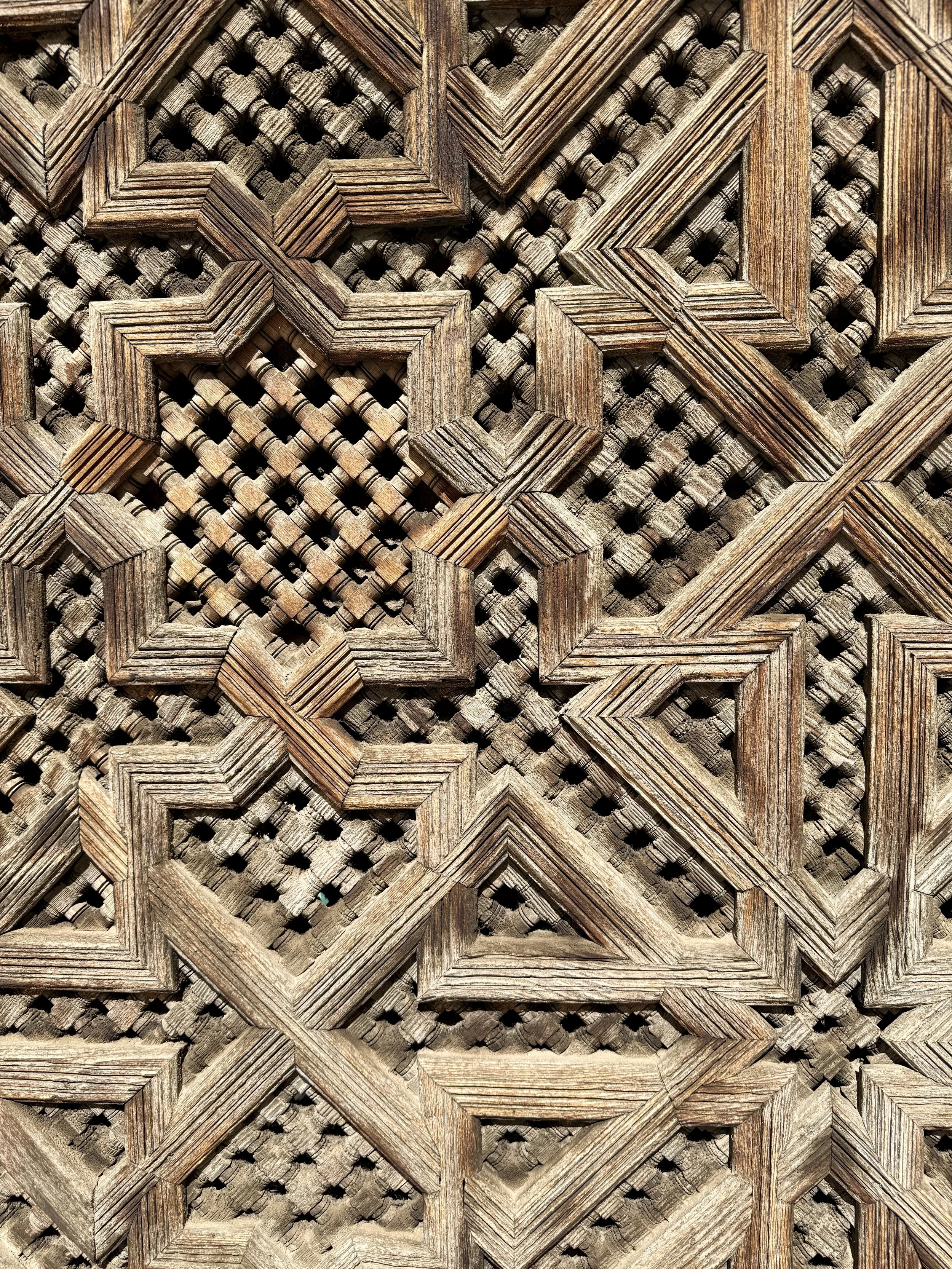 Close-up view of a wooden lattice or decorative panel with intricate geometric patterns and interwoven textures.