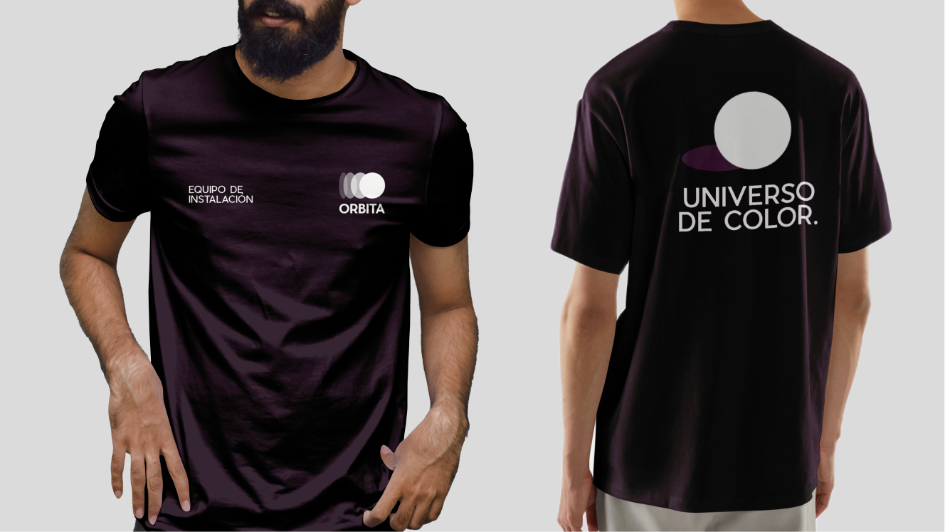 Two models wearing black T-shirts with colorful celestial graphics and Spanish text, one showing the front and the other the back of the shirts.