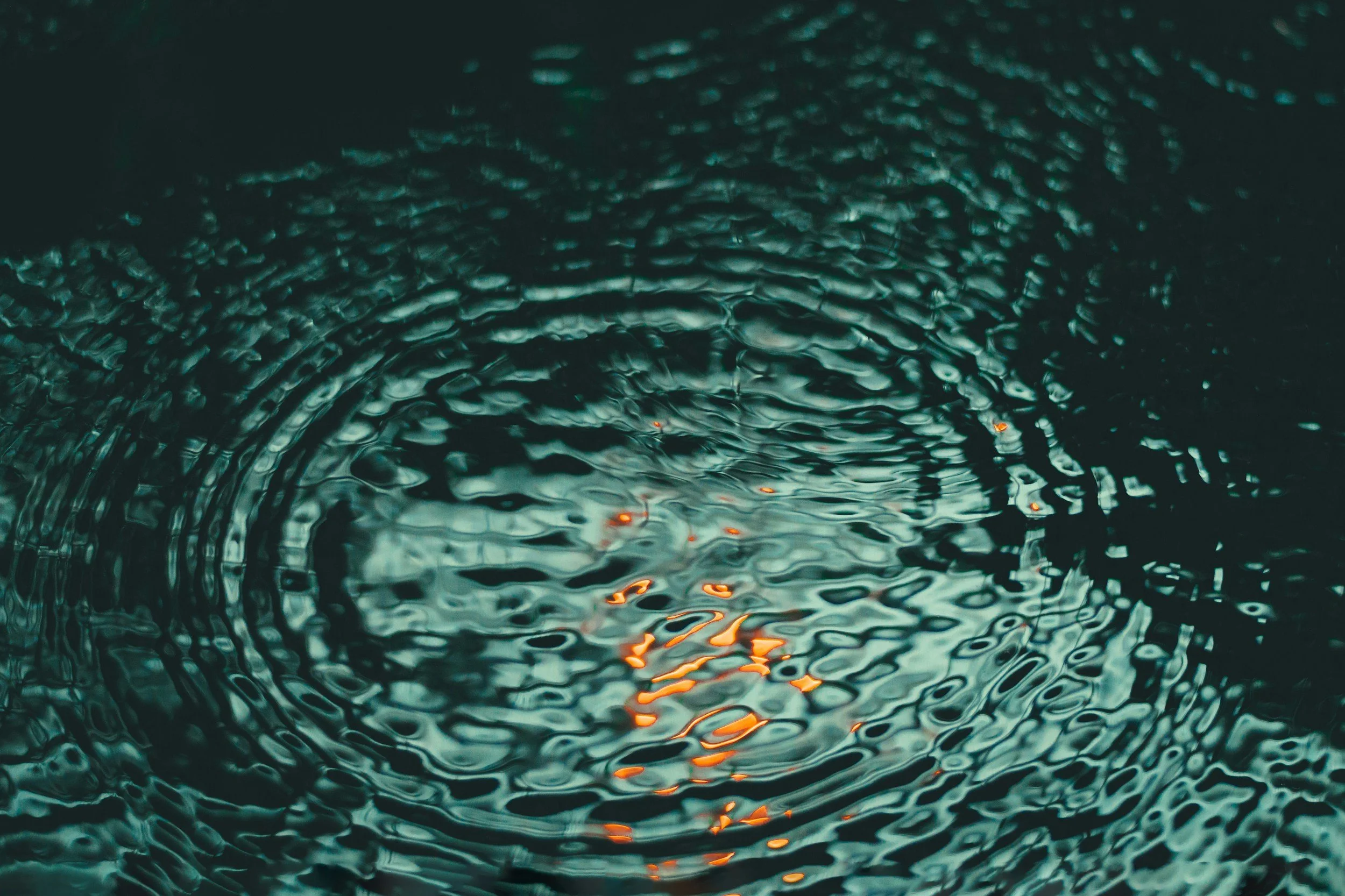 Close-up of water with ripples and light reflections, creating a textured surface.