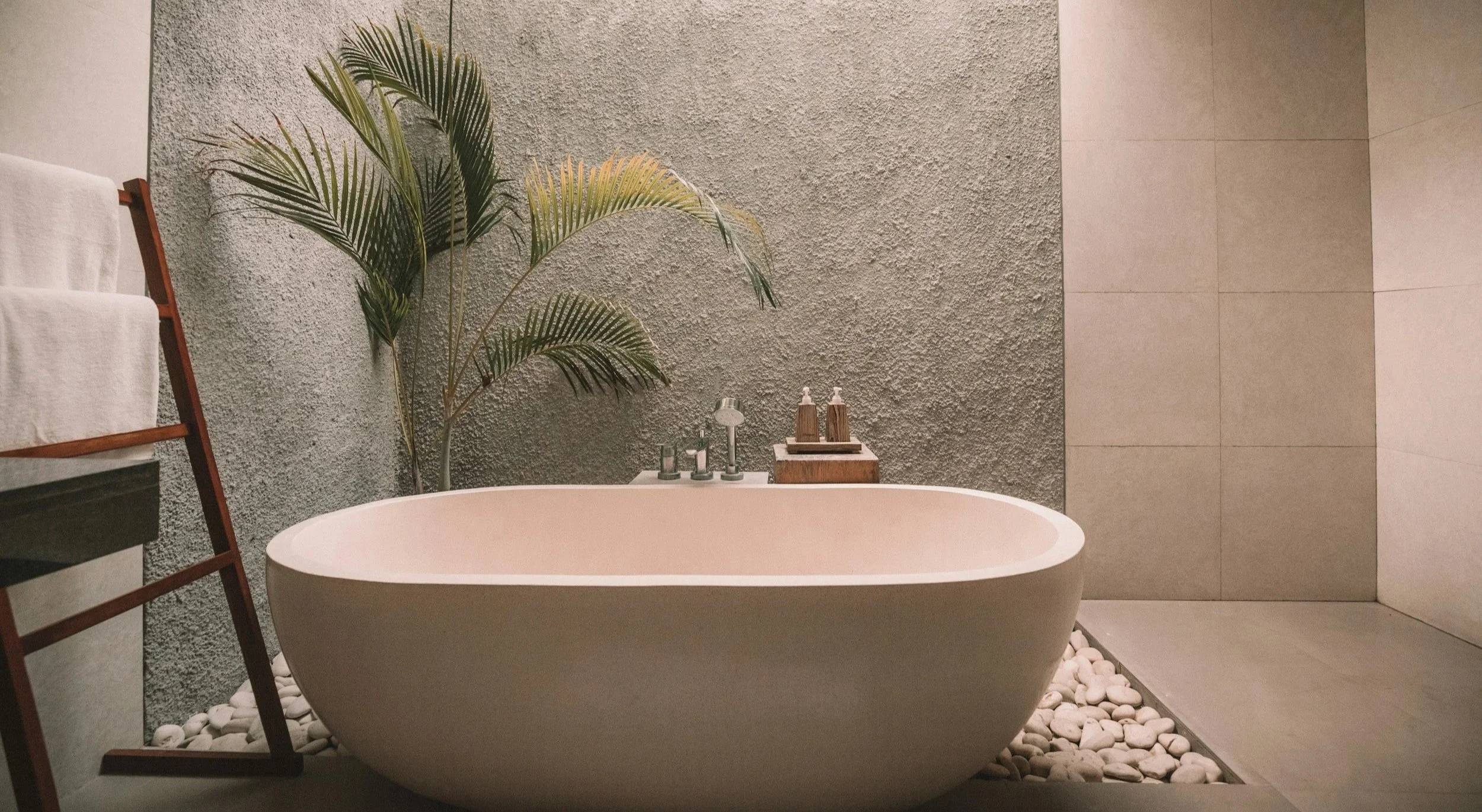 Modern bathroom with a freestanding bathtub, lush green plants, and minimalist decor.