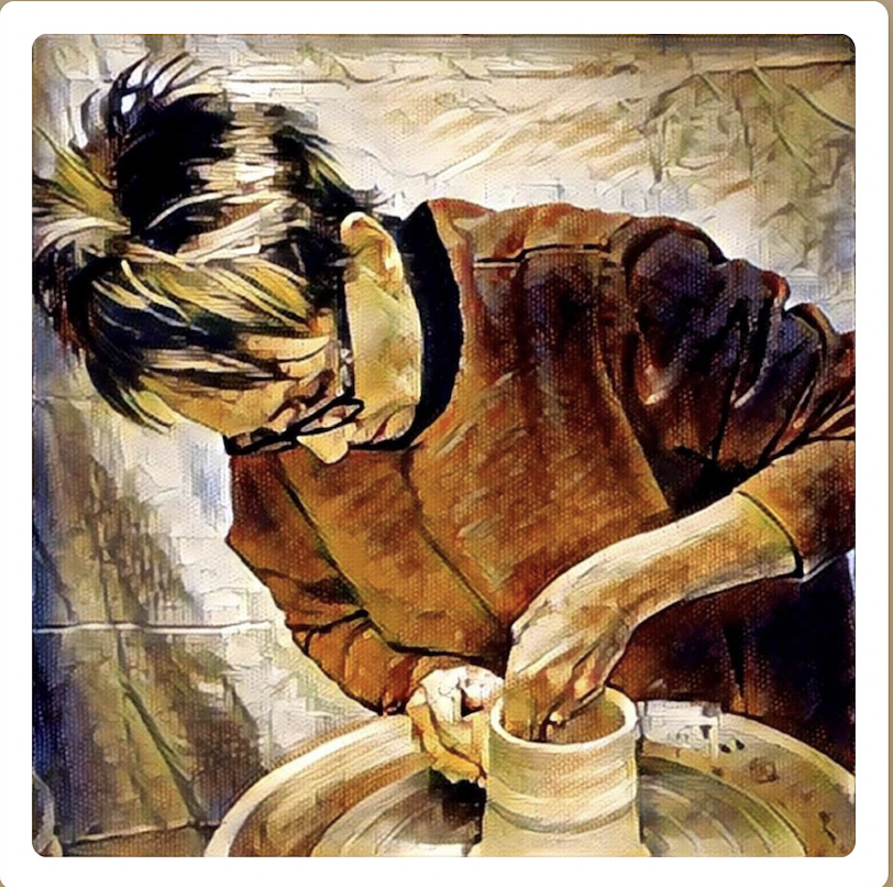 Person working on a pottery wheel, shaping clay with hands.