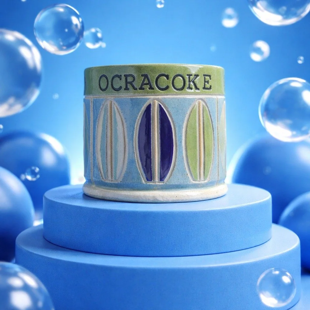 A ceramic container with the word 'OCRACOKE' on it, decorated with colorful geometric patterns, placed on a blue platform against a background of floating bubbles and a blue sky.