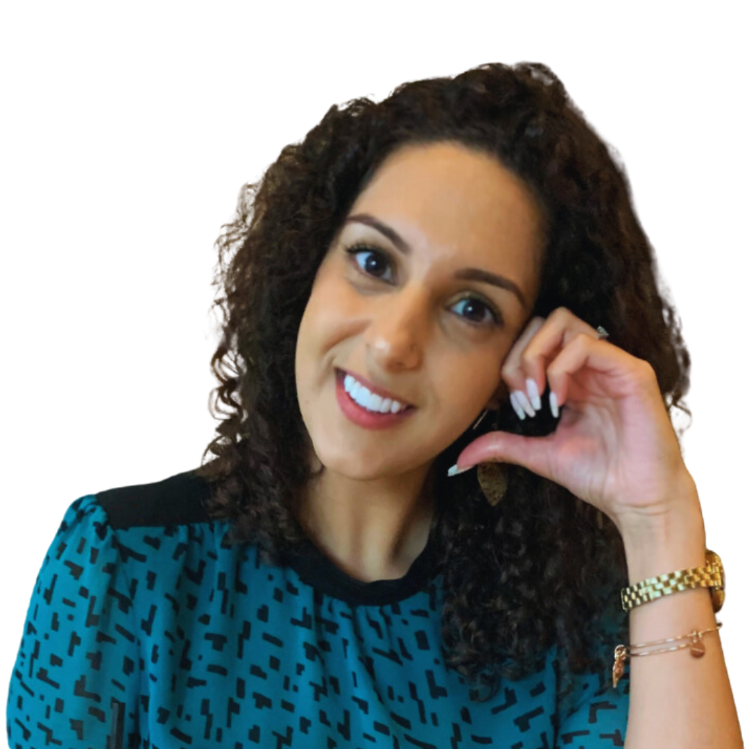 A woman with curly dark hair smiling, wearing a blue patterned top, a gold watch, and bracelets, holding her head with her hand.