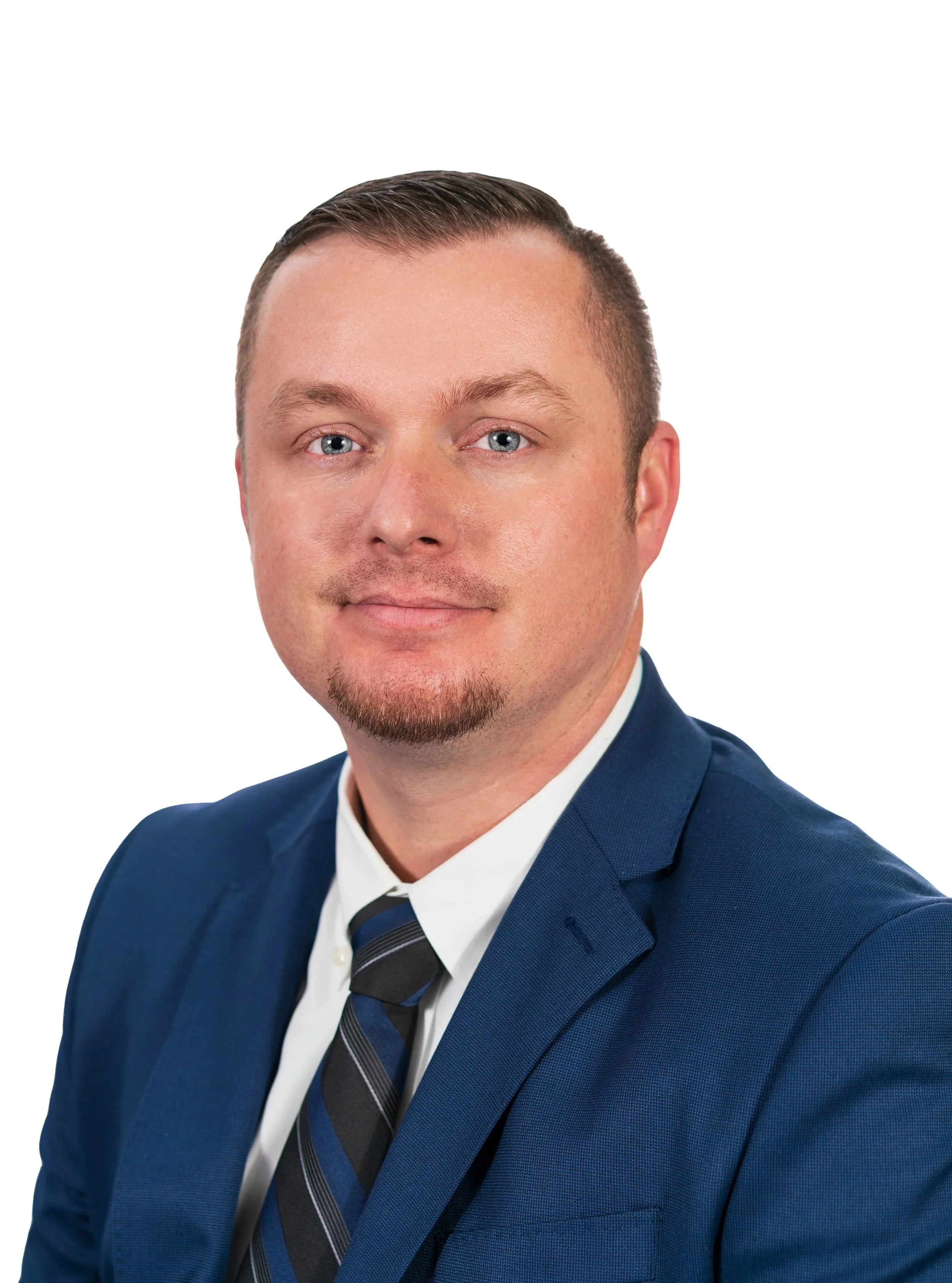Portrait of a man in a blue suit, white shirt, and striped tie, with short neatly styled hair and a goatee, against a plain white background.