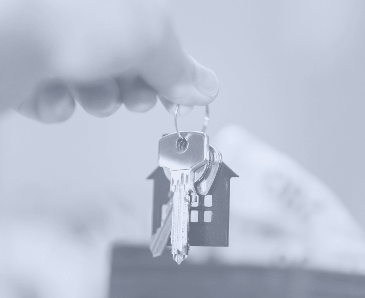 Close-up of a hand holding a keychain with house-shaped and house key symbols.