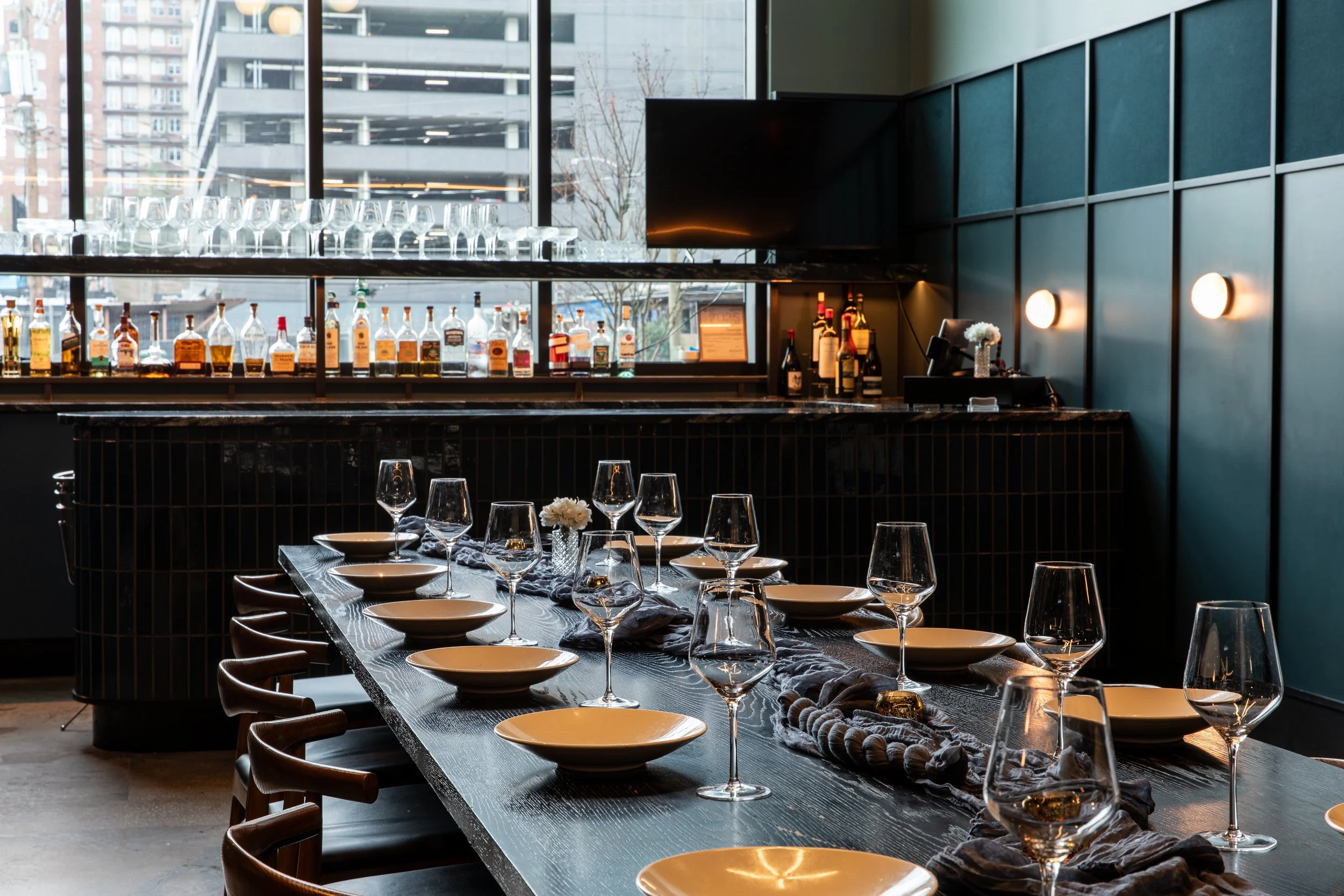 A long private dining table set with wine glasses in front of the bar