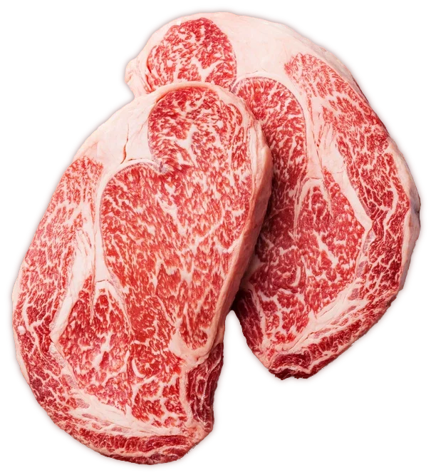 Two heavily marbled Wagyu ribeye steaks on a black background