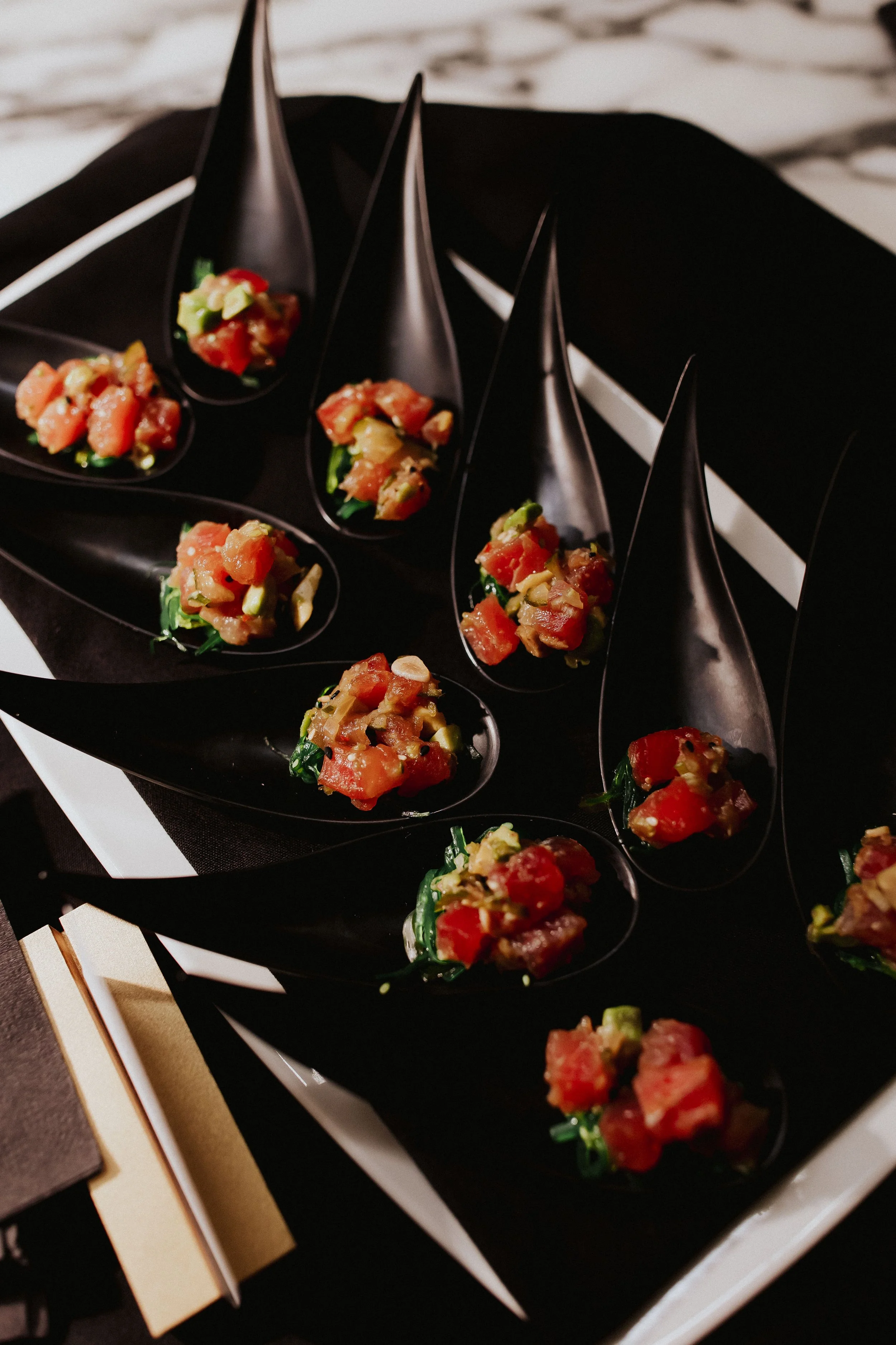 Canapés served on spoons on a dark table