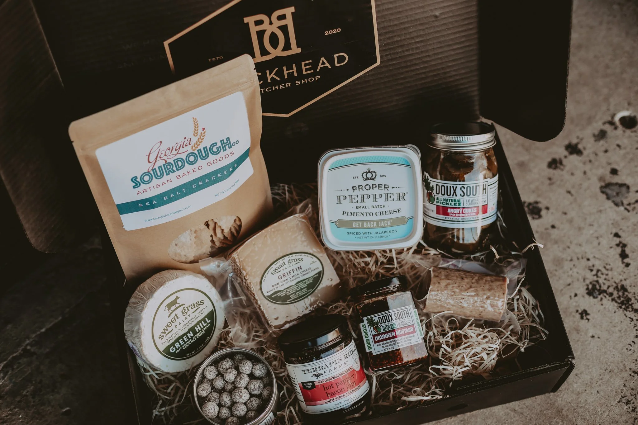 A gift box with sourdough, seasoning and jars of spreads on kraft paper filler