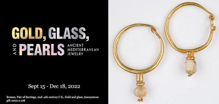 Brochure for an exhibition about ancient Mediterranean jewelry featuring gold, glass, and pearl pieces, with an image of gold earrings with pearl drops on the right side.
