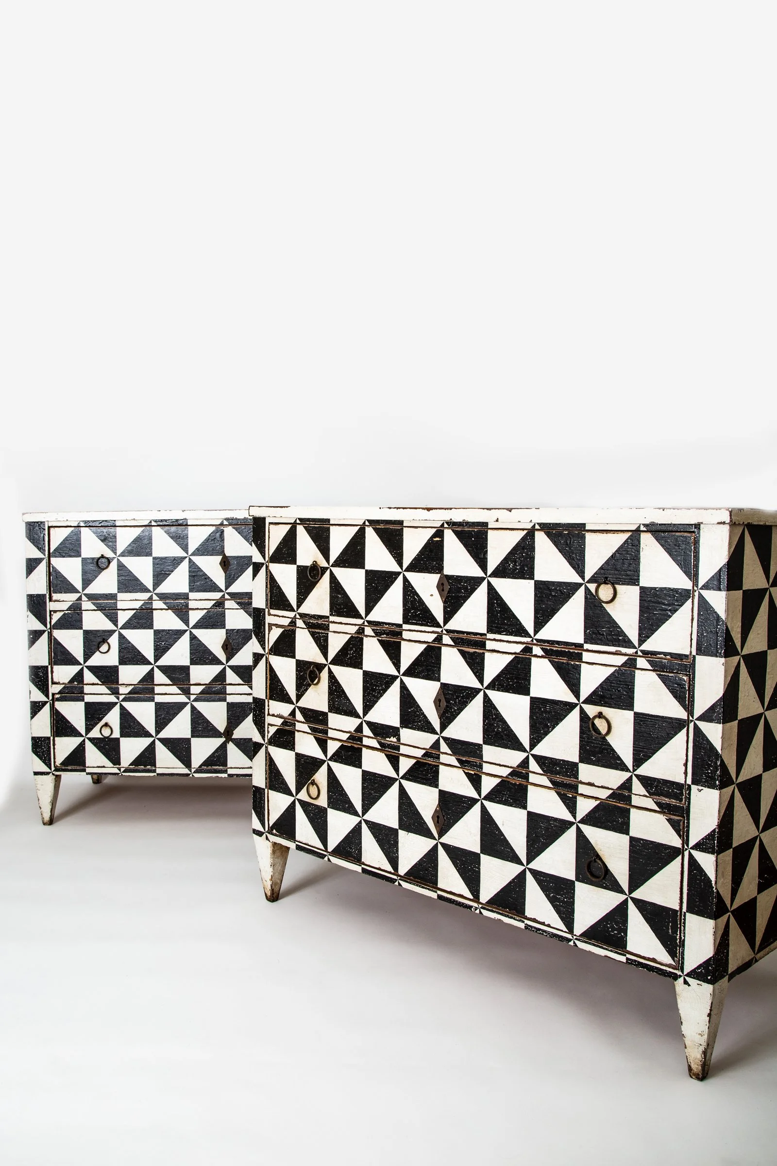 A vintage wooden dresser with a black and white geometric triangle pattern on the doors and drawers, slightly distressed, standing on a plain white background.