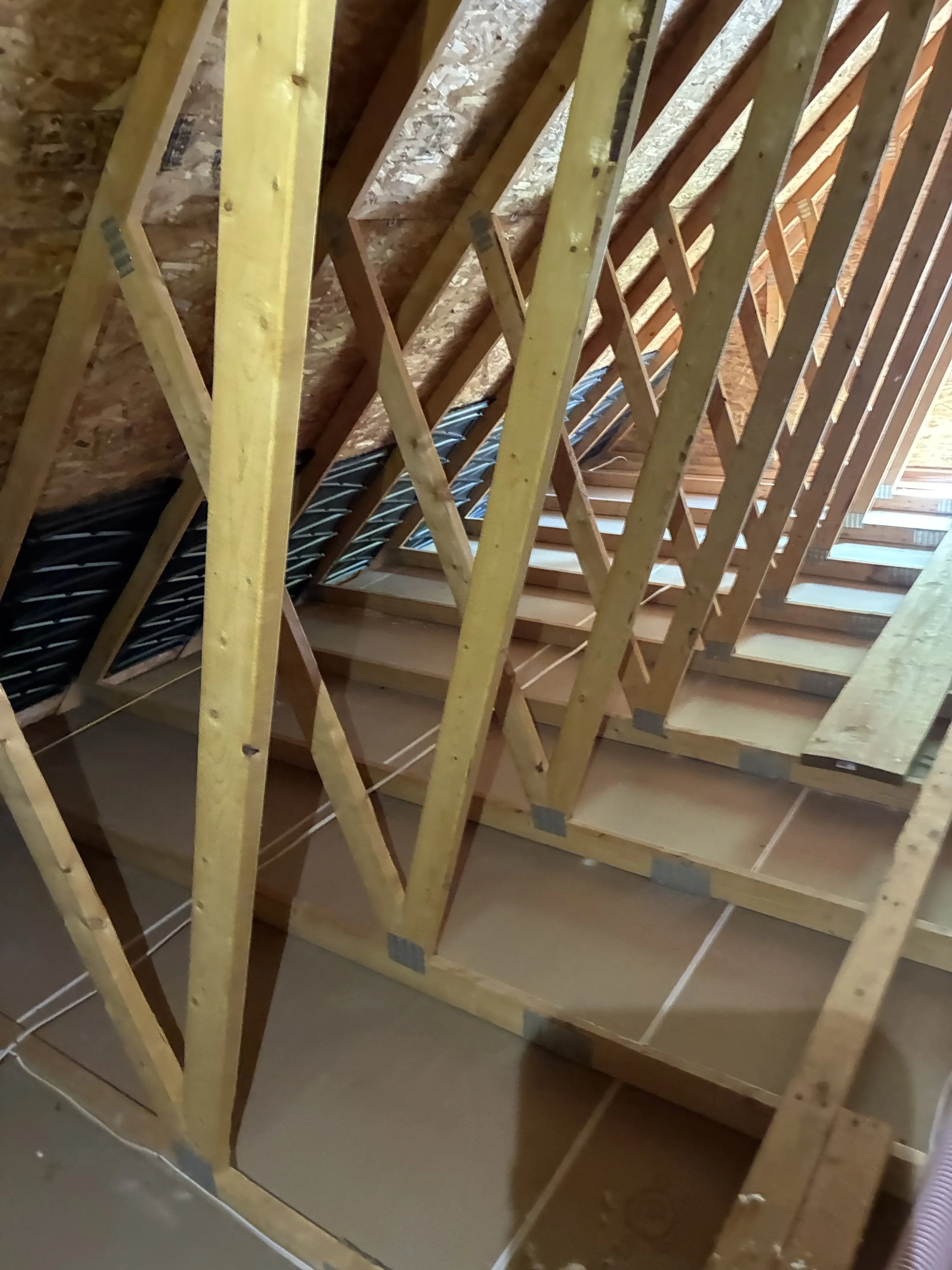 Interior view of a house under construction showing wooden framing and insulation.