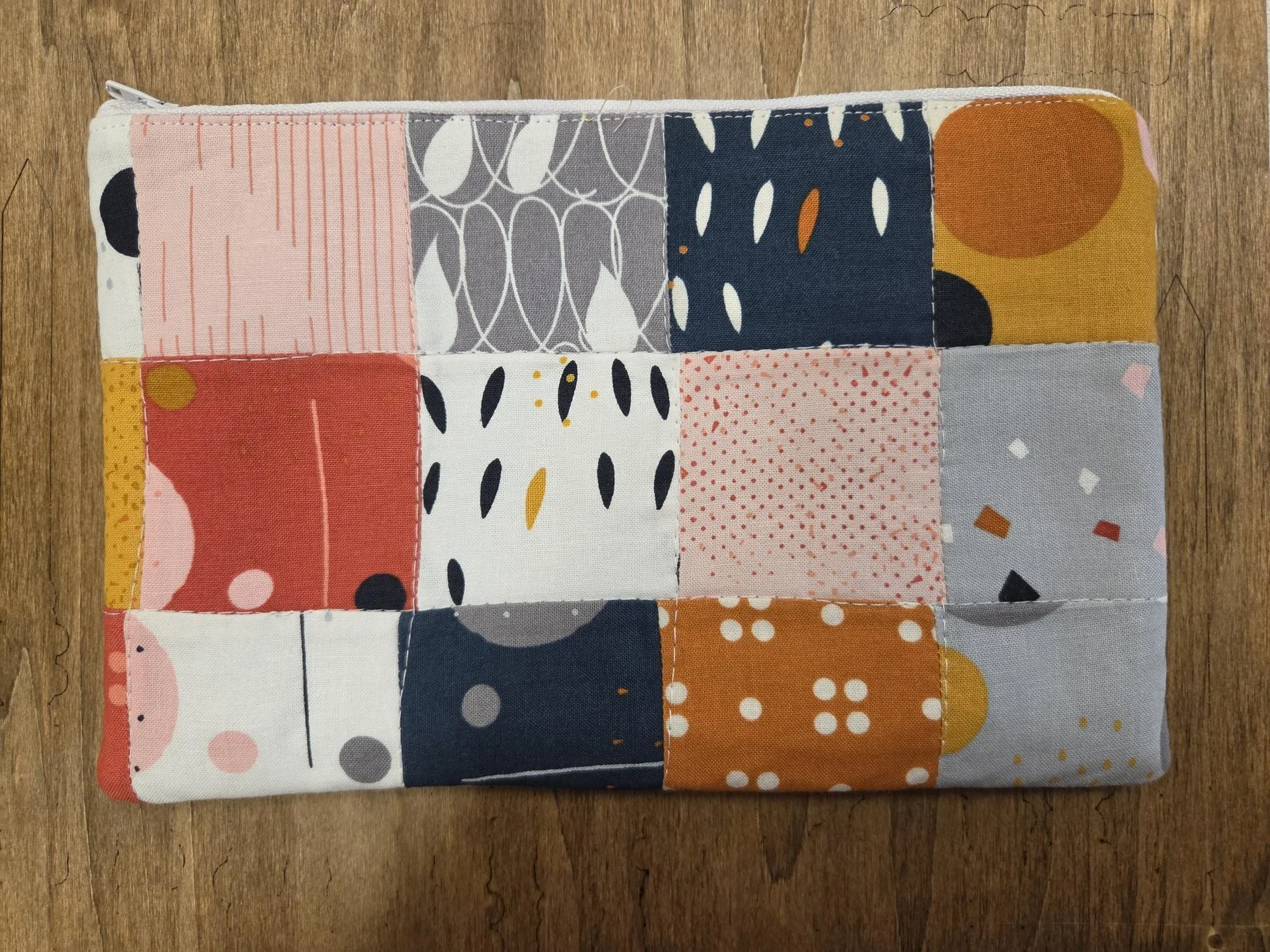 Handmade colorful patchwork zipper pouch featuring coral, blush, mustard, navy, cream and gray patterned cotton fabrics.