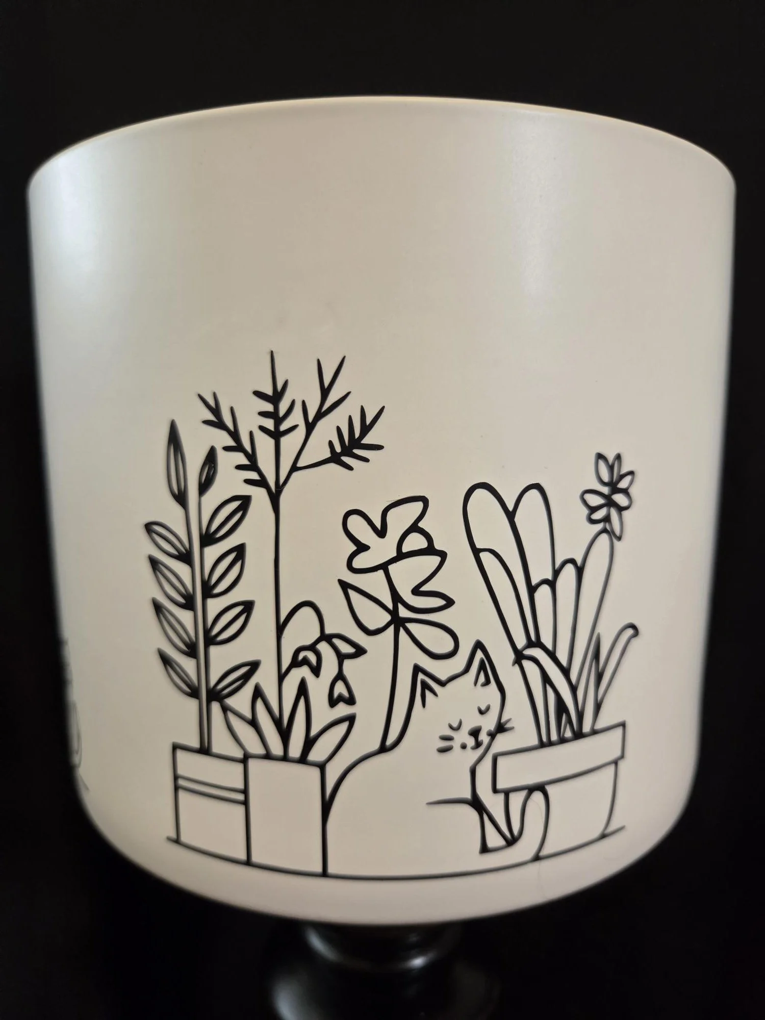 Large ceramic planter featuring four minimalist illustrations of sleeping cats surrounded by houseplants wrapped around the entire planter, available in black or white.