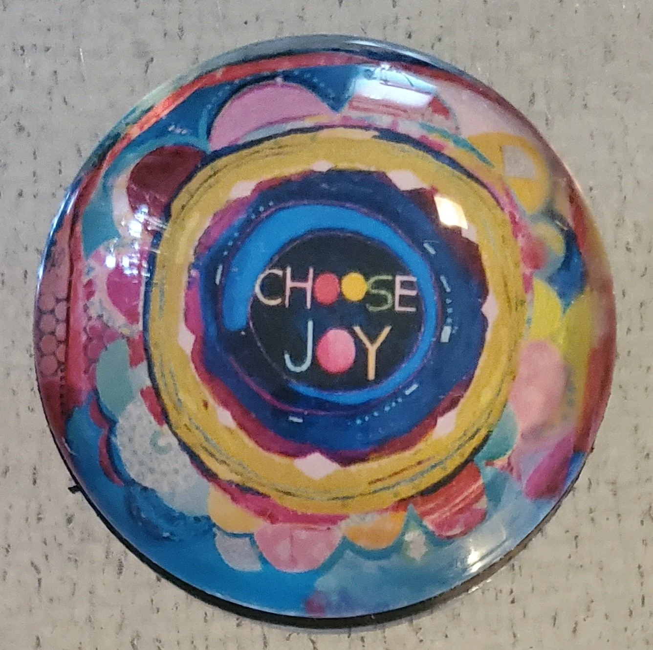 Handmade 2-inch round glass magnet featuring the words "Choose Joy" surrounded by colorful abstract concentric circles beneath a crystal-clear glass dome.