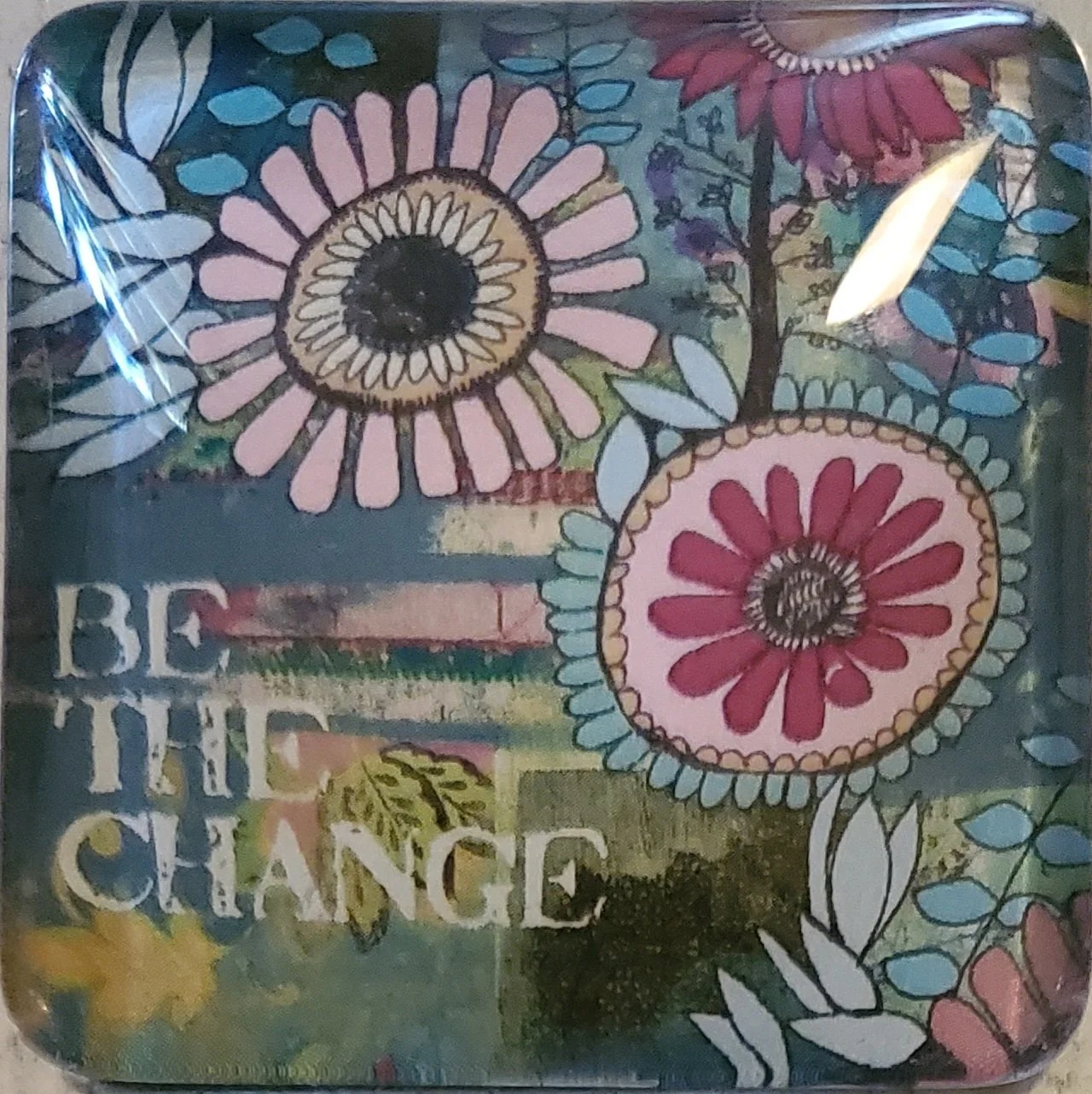 Handmade 2-inch crystal glass magnet featuring colorful floral artwork and the inspirational phrase "Be the Change."