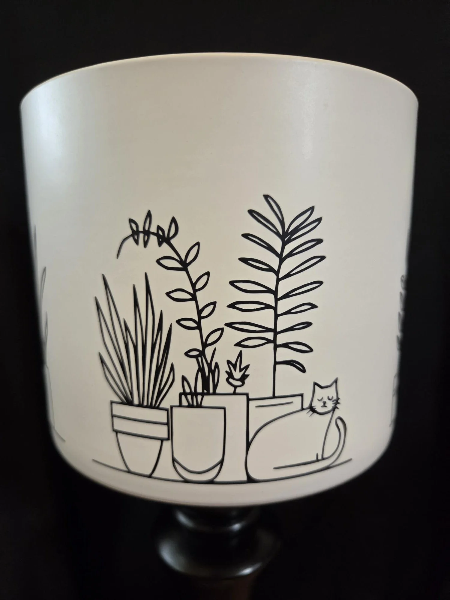 Large ceramic planter featuring four minimalist illustrations of sleeping cats surrounded by houseplants wrapped around the entire planter, available in black or white.