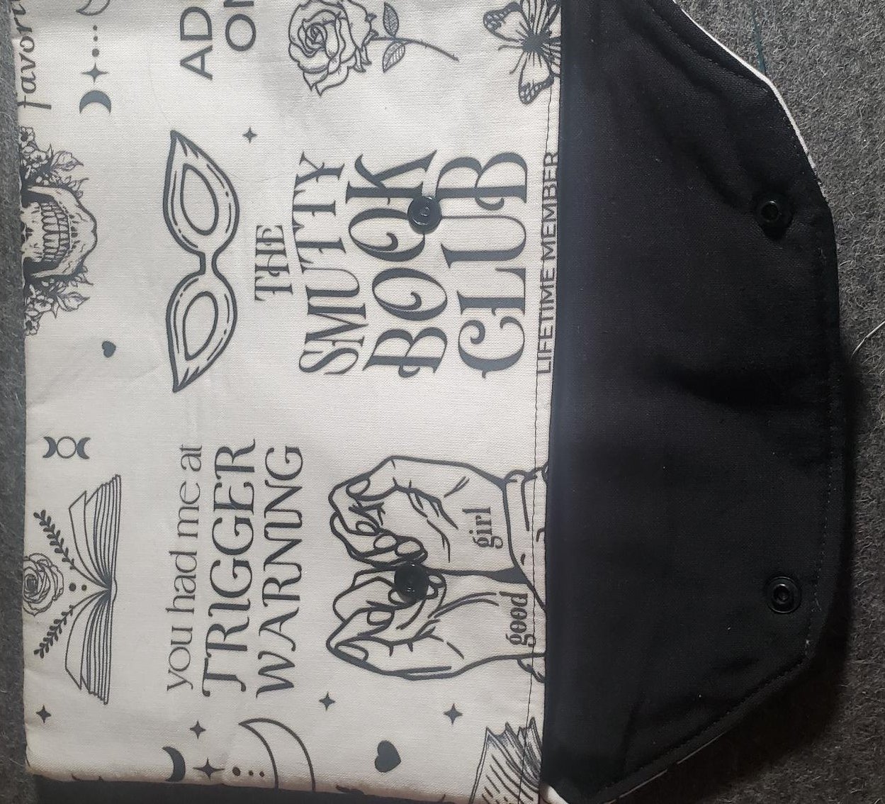 Large handmade padded book sleeve featuring dark academia book club themed cotton fabric with literary illustrations, roses, books, moons, and a secure snap closure.