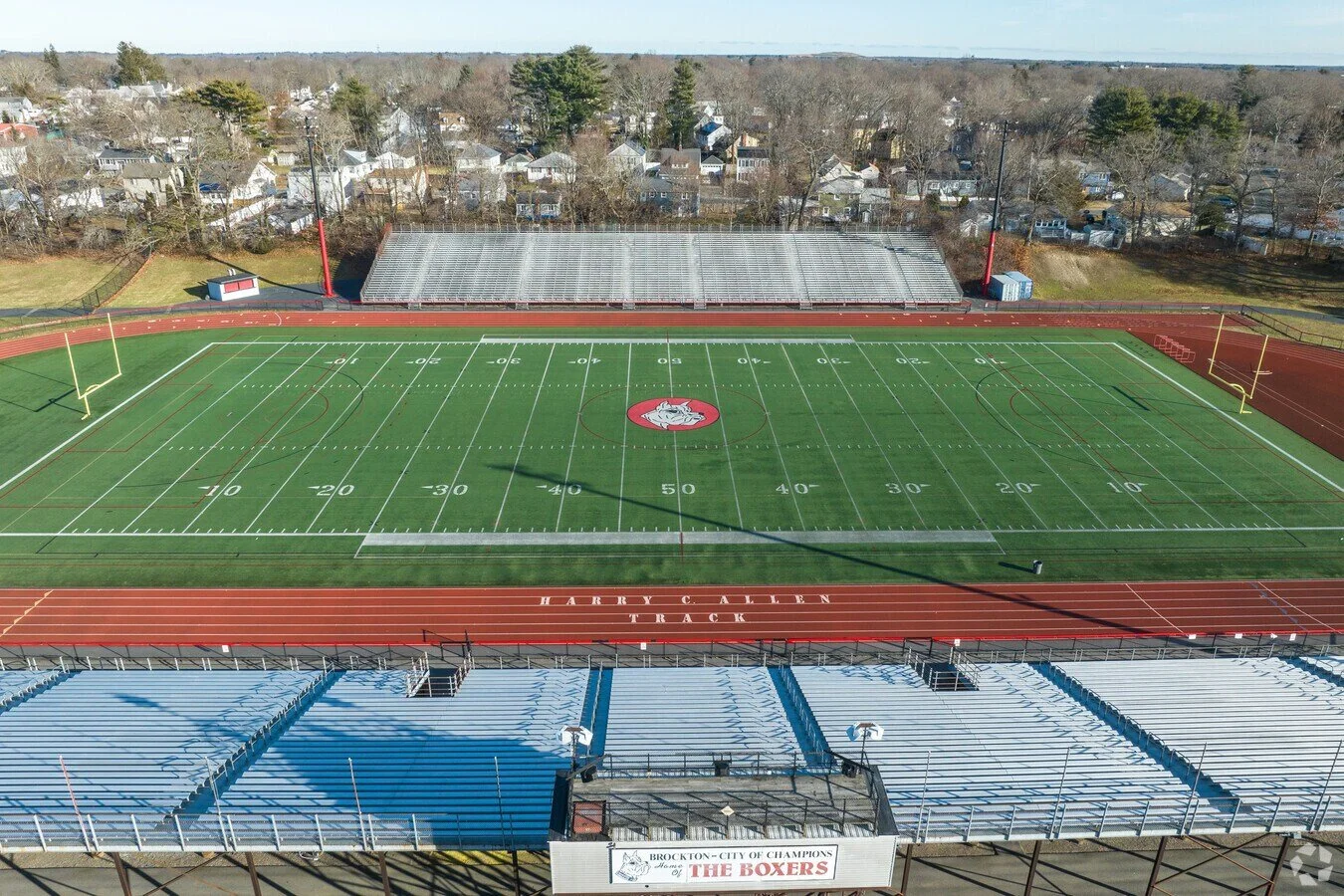 Empty football stadium with a field and bleachers, surrounded by a running track labeled 'Tarry Allen Track.' Residential houses are visible in the background.