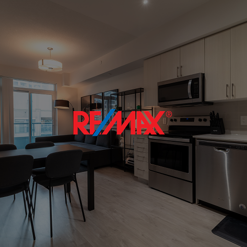Open kitchen and dining area with black dining table, five black chairs, stainless steel appliances, and large window with balcony door.