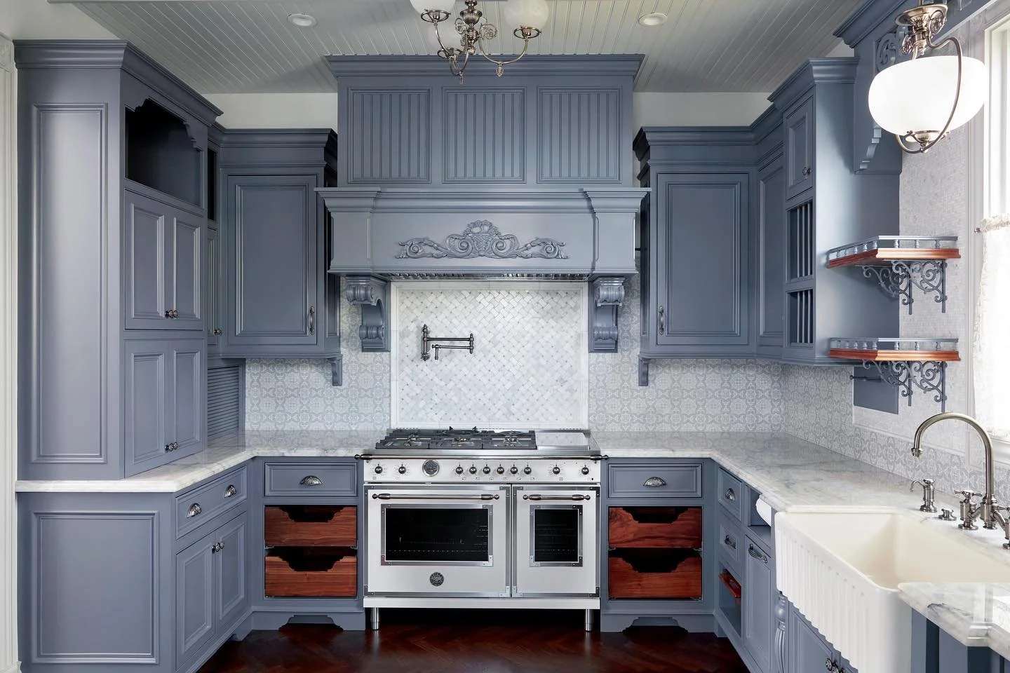 Kitchen with blue cabinets, marble countertops, a vintage stove, and decorative shelves.
