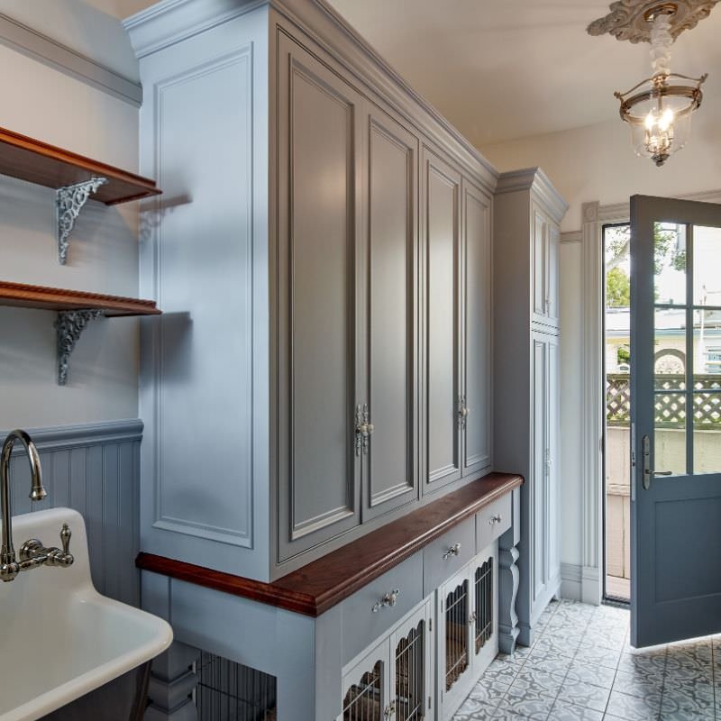 Kitchen with painted cabinets, open door leading outside, and decorative ceiling light.