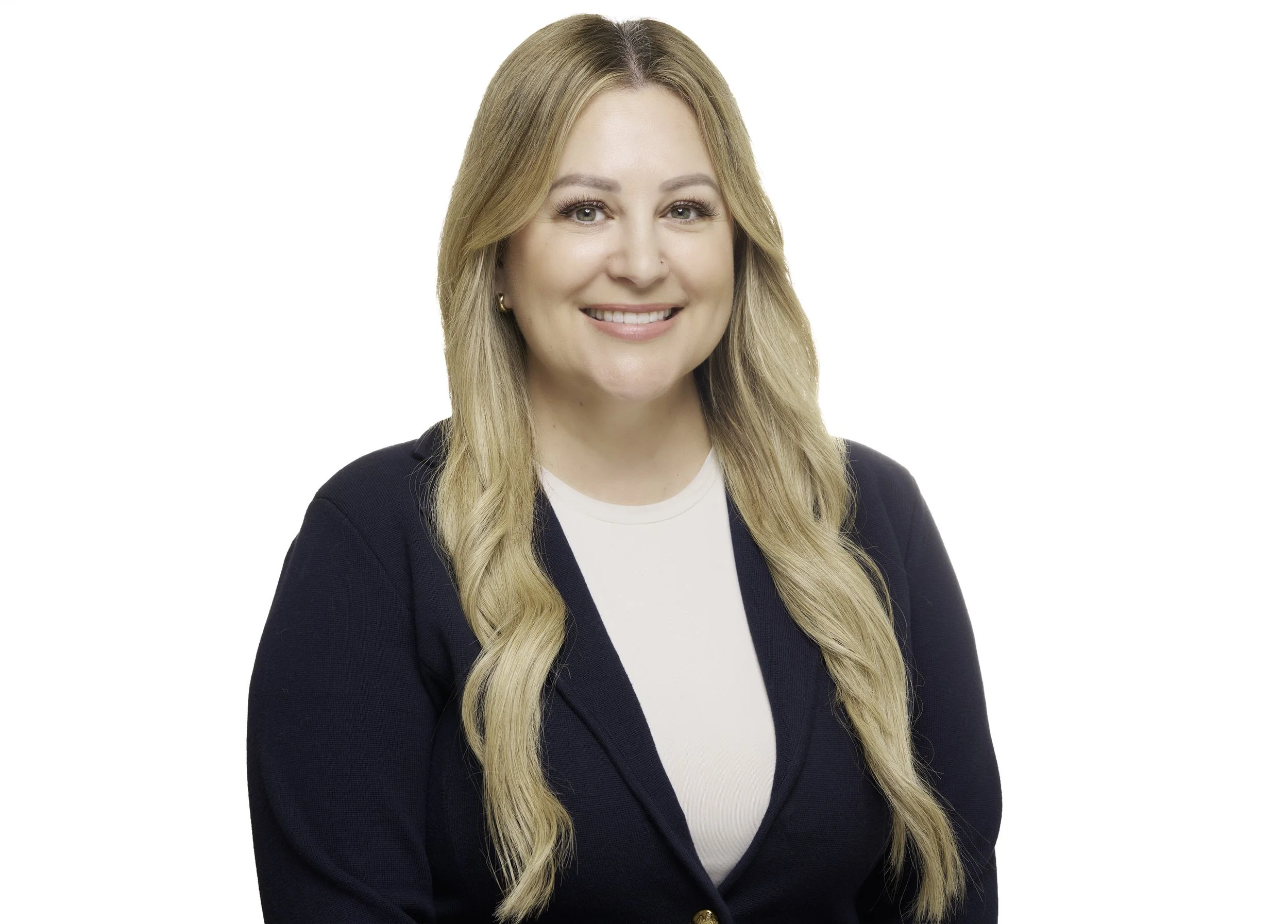 A professional woman with long blonde hair, smiling, wearing a navy blazer and white top, posing against a white background.