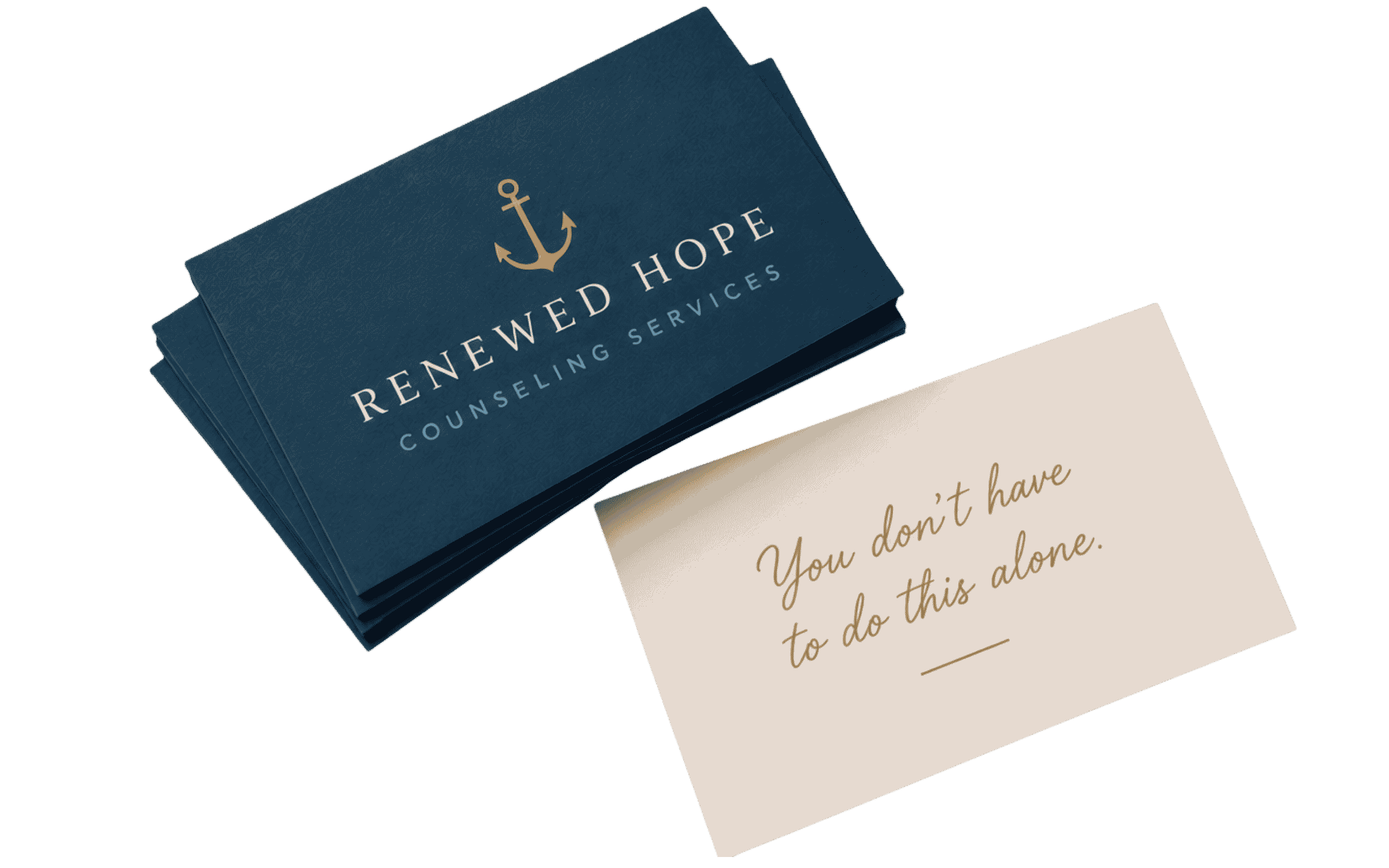 Business cards with a navy blue background and a gold anchor logo, reading "Renewed Hope Counseling Services"; partially visible handwritten note with cursive text that says "You don't have to do this alone."