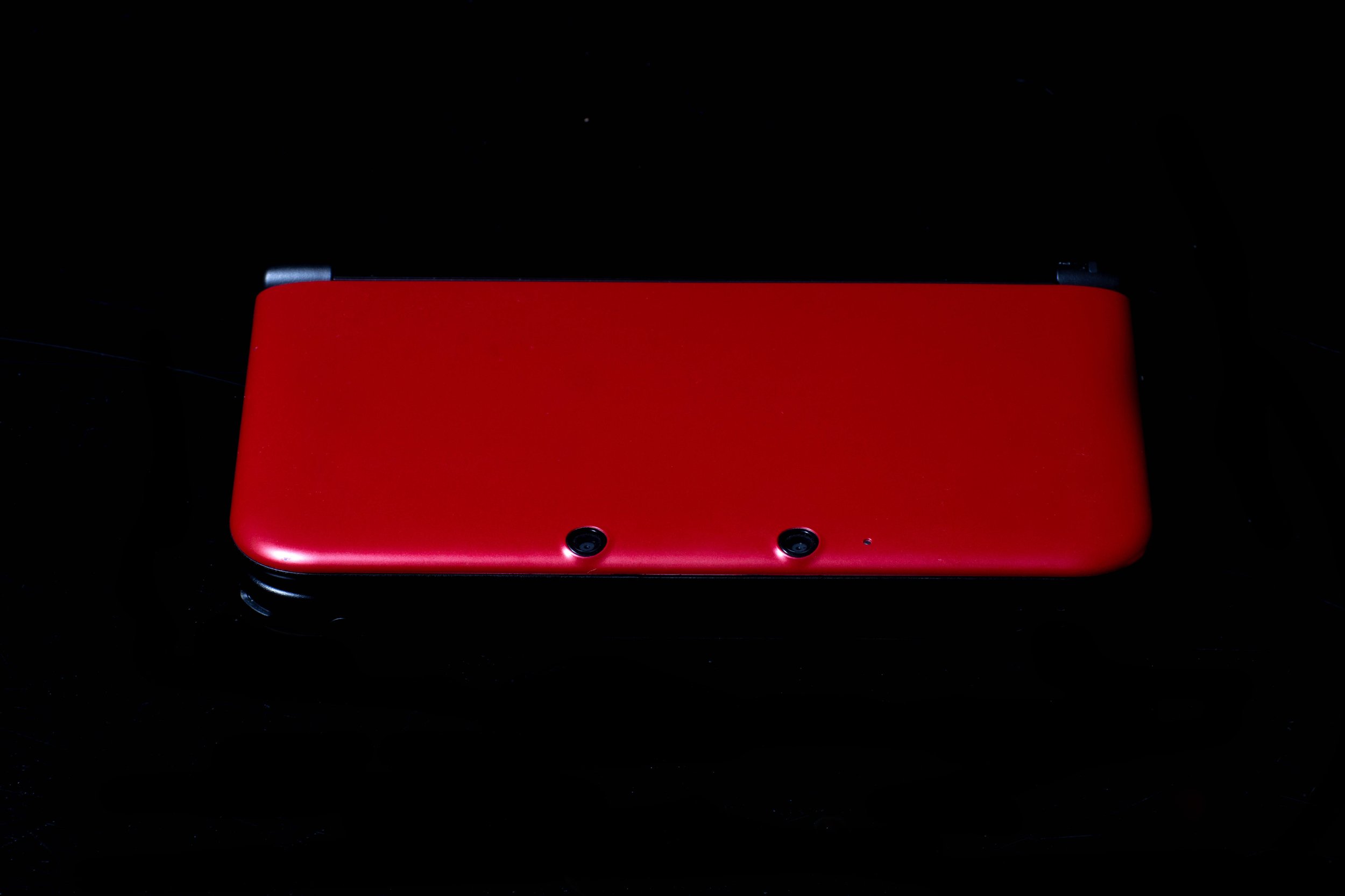 Red Nintendo Switch gaming console with controllers attached, shown against a black background.