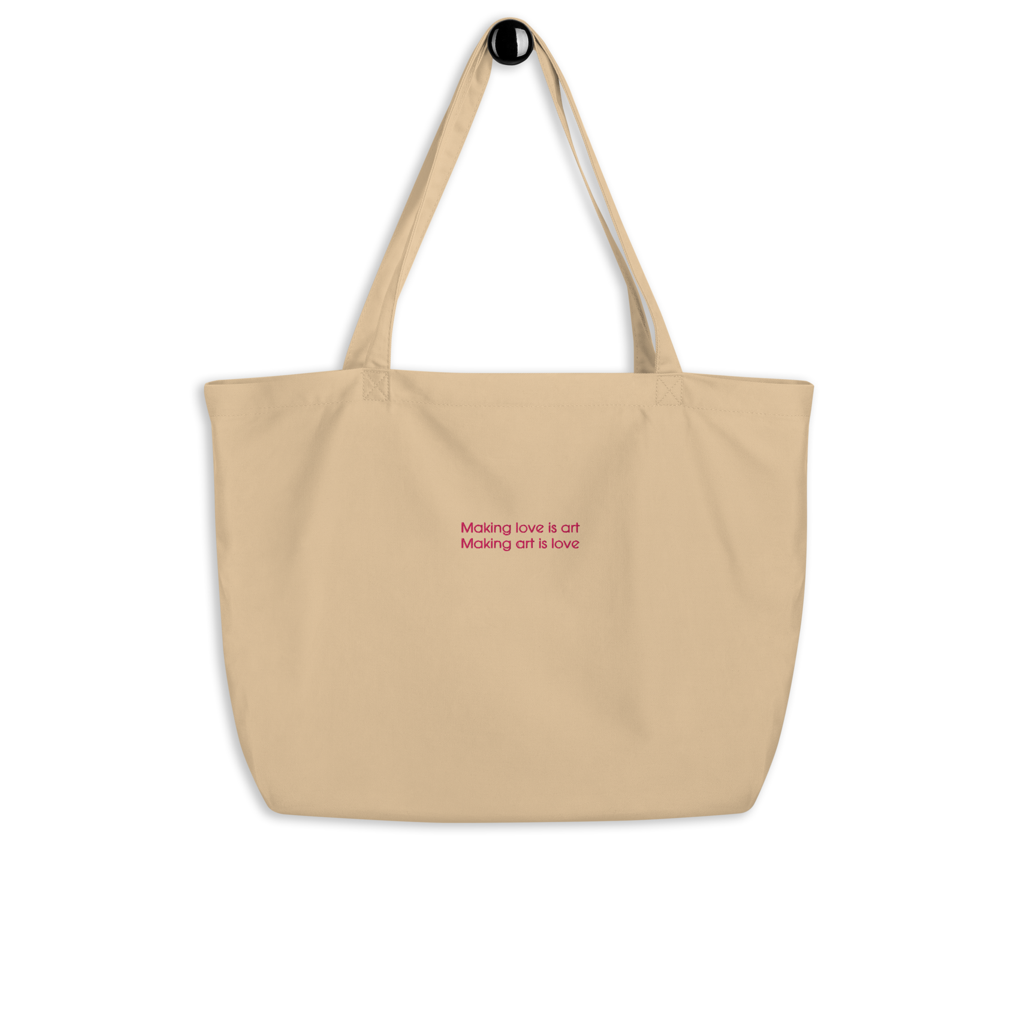A beige tote bag with pink text that reads "Making love is art Making art is love" against a black background.