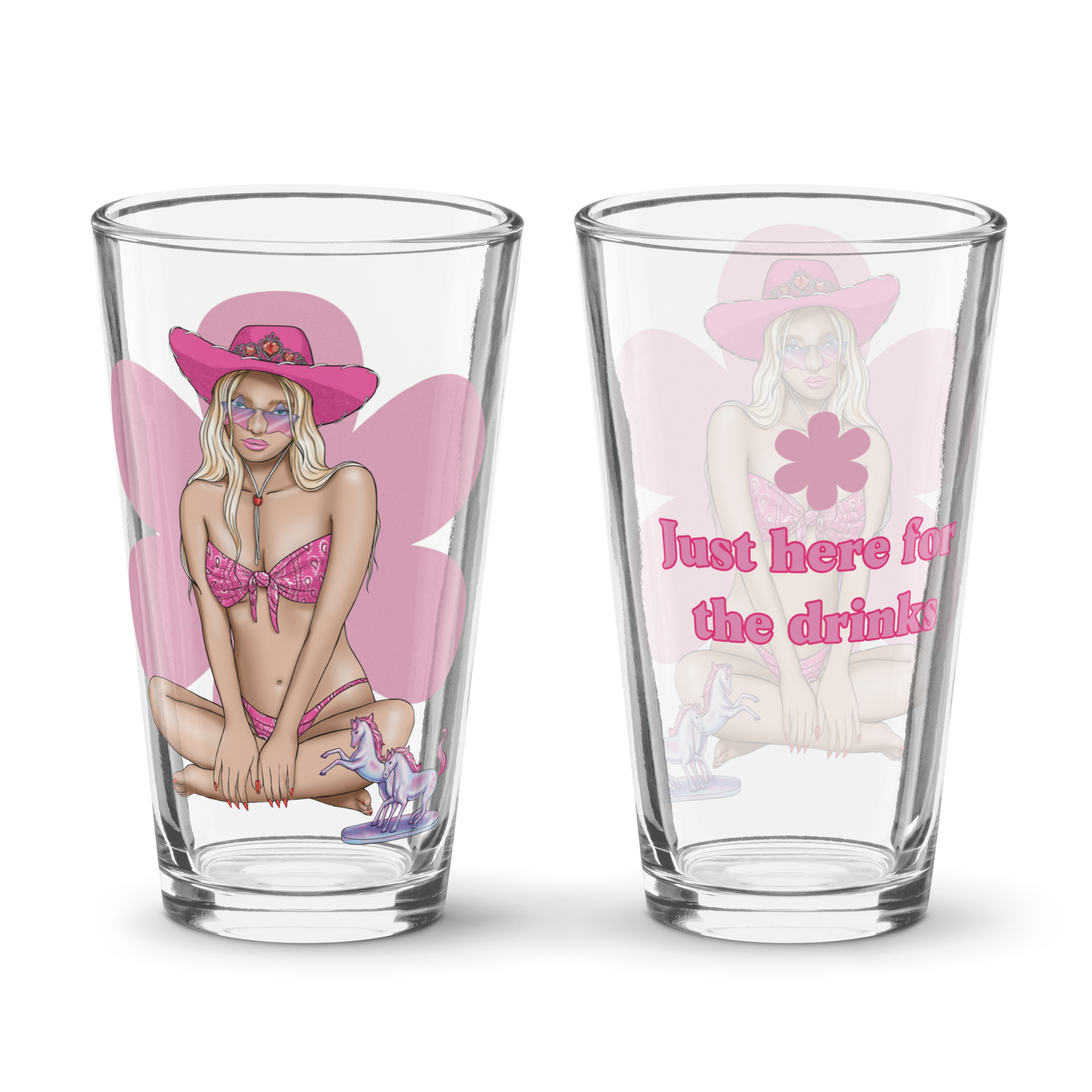 Two clear glass tumbler glasses with colorful illustrated designs of a woman in pink attire and unicorns, with text on one that reads 'Just here for the drinks'.