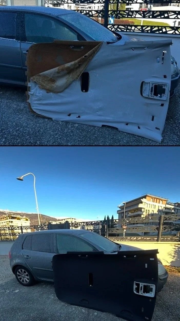 Une voiture grise avec une pièce de porte déconnectée posée devant elle