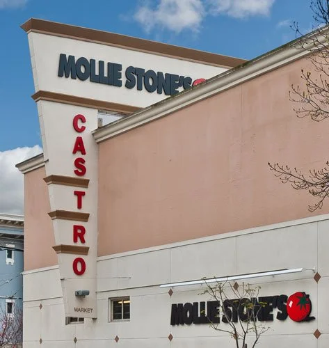 Exterior view of a building with a large sign that reads 'Molle Stones'. The building has a pink and white facade with the word 'Cafeteria' written vertically in red letters on the corner. There is also a smaller sign with the same name and a red che