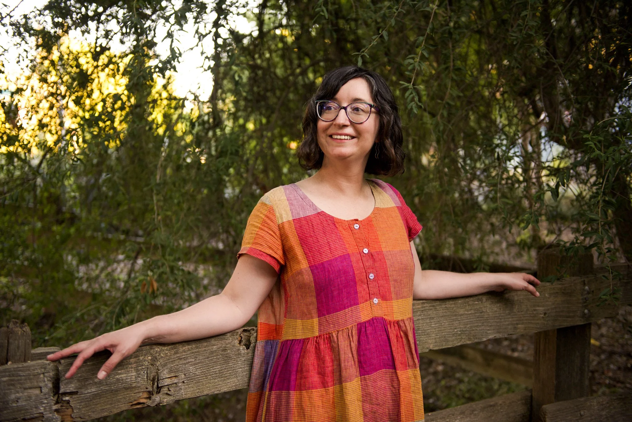 Rebecca Huval, grief therapist, leans her back against a fence in the Sacramento State Arboretum. Rebecca works with disenfranchised grief, including infertility, chronic illness, and pet loss.
