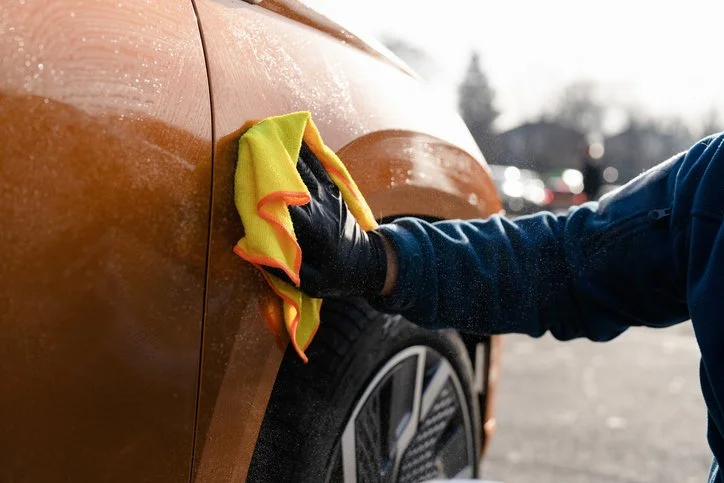 wiping a orange car with yellow cloth