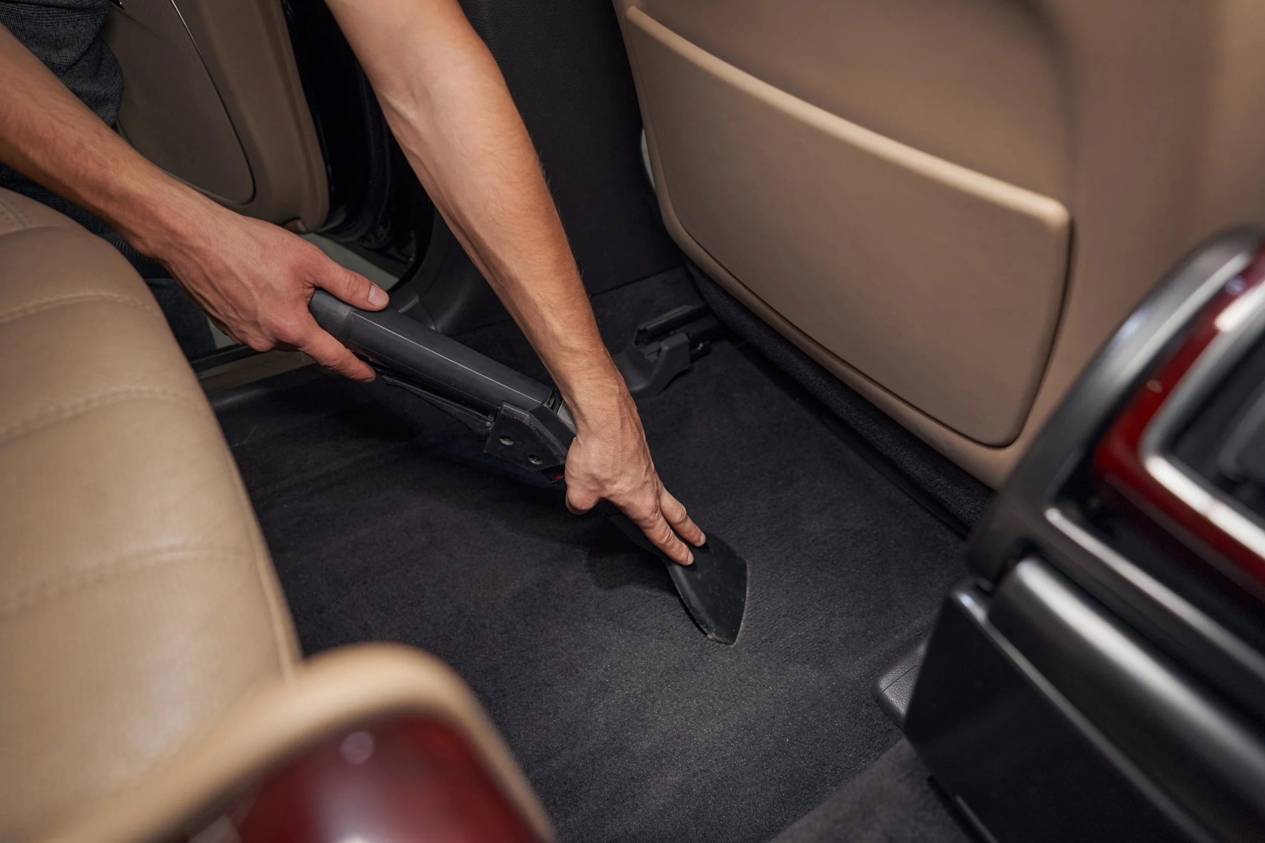 hoovering a rear carpet of a car