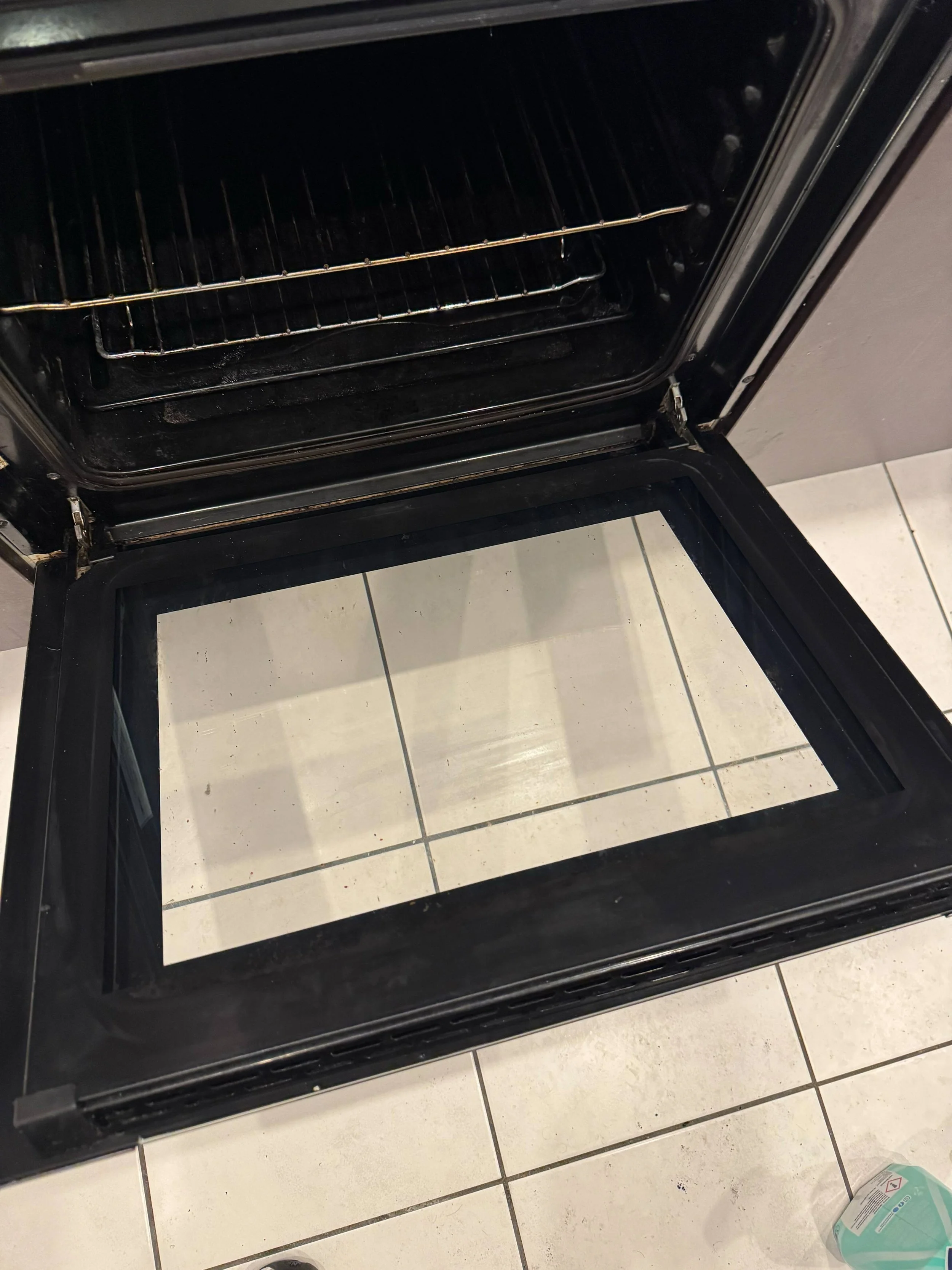 Oven with the door open, showing the interior racks and a baking sheet.