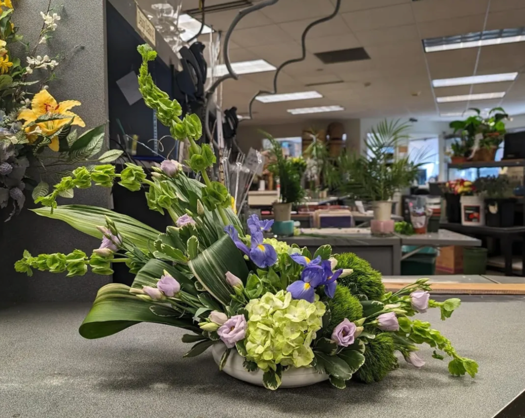 Asymmetic - iris, lisianthus, bells of ireland, hydrangea, dianthus, variegated pittosporum & variegated aspidistra