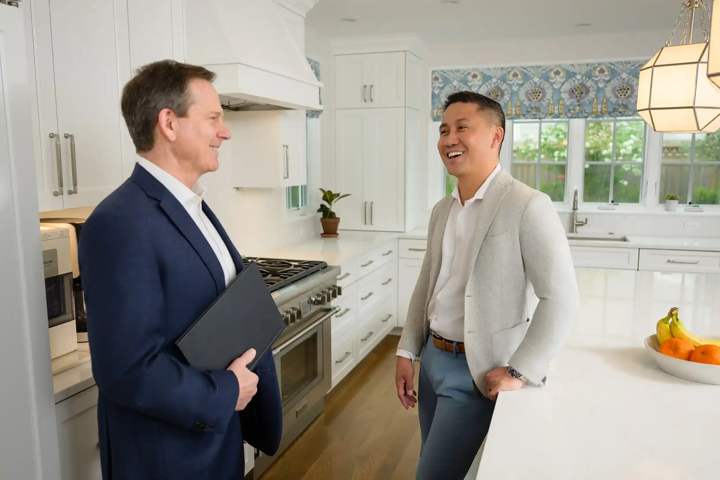 Jeff Beall smiling and engaging in conversation with a client in a bright, white kitchen