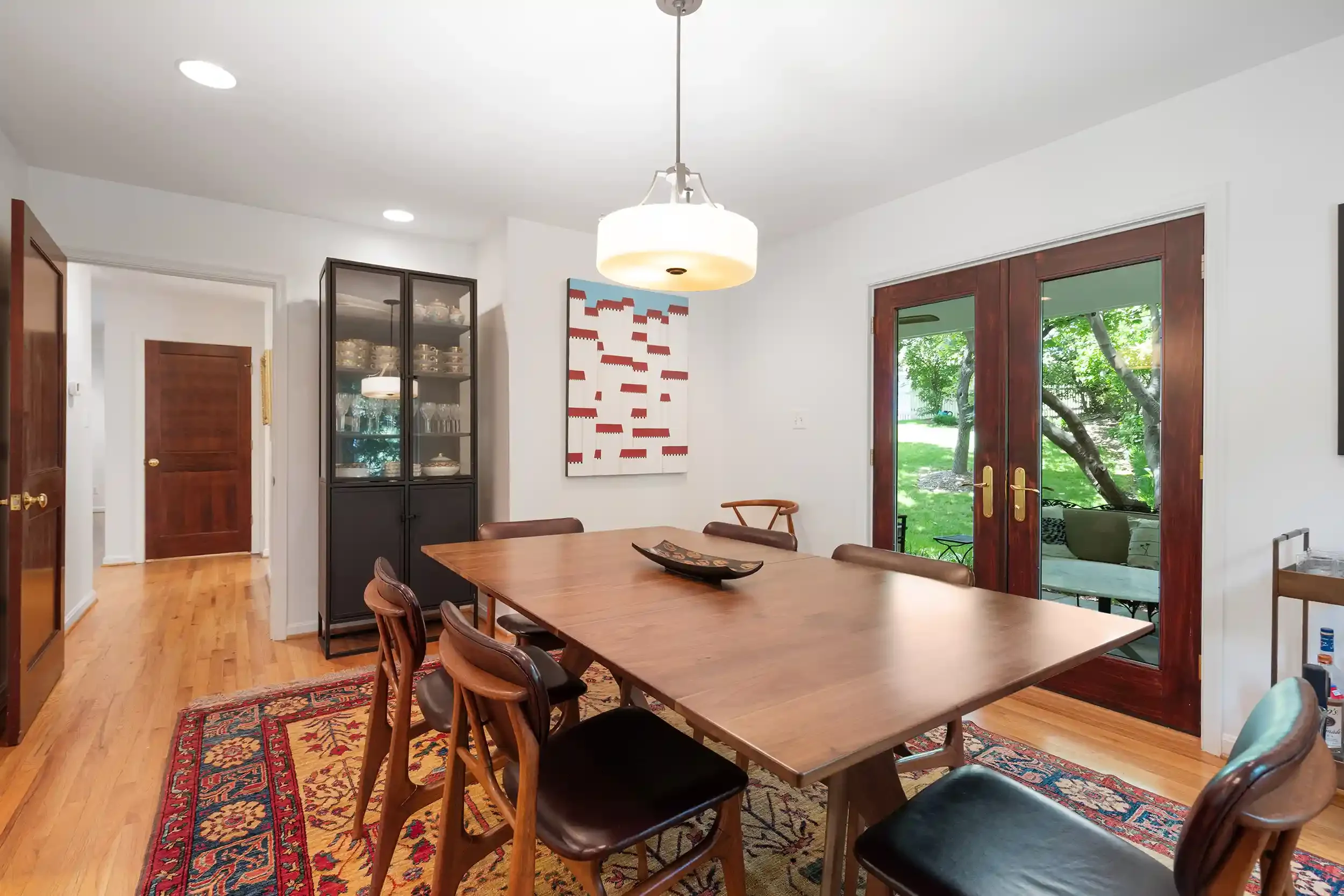 A dining room with wooden flooring and a large rectangular wooden table with chairs around it