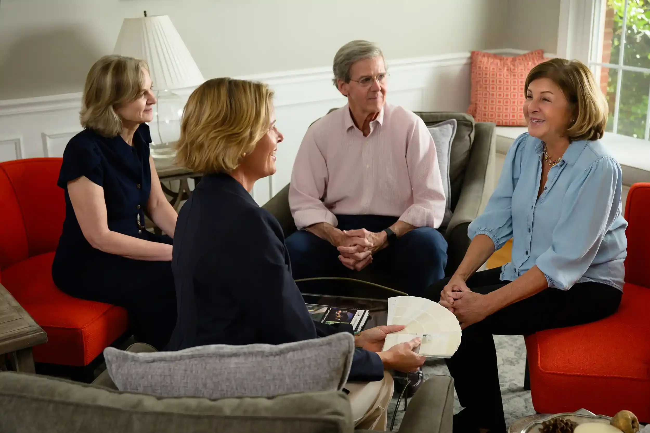 Alex Beall and Kathy Rehill sitting with clients in a living room, engaged in conversation