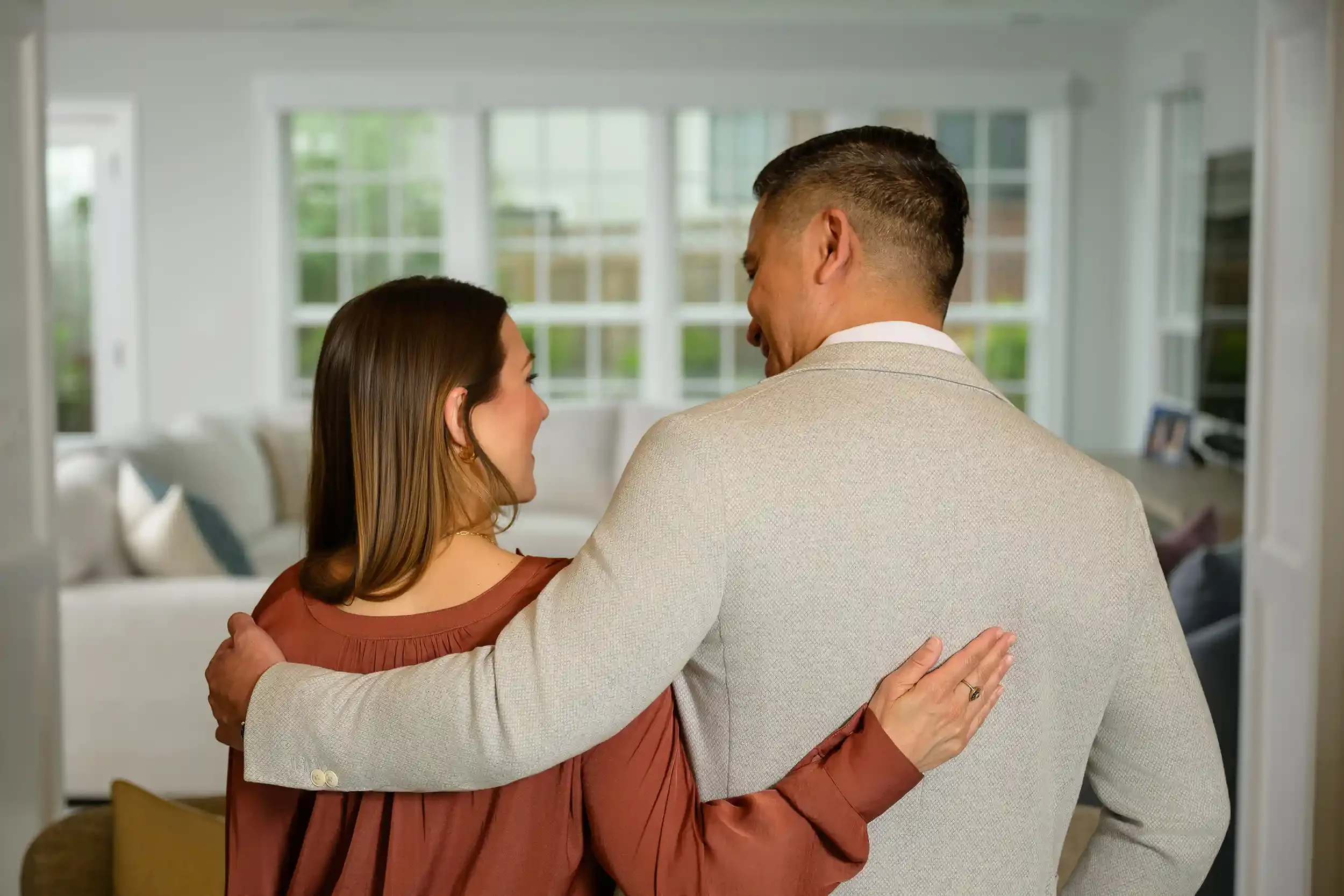A husband and wife embrace each other indoors their new home