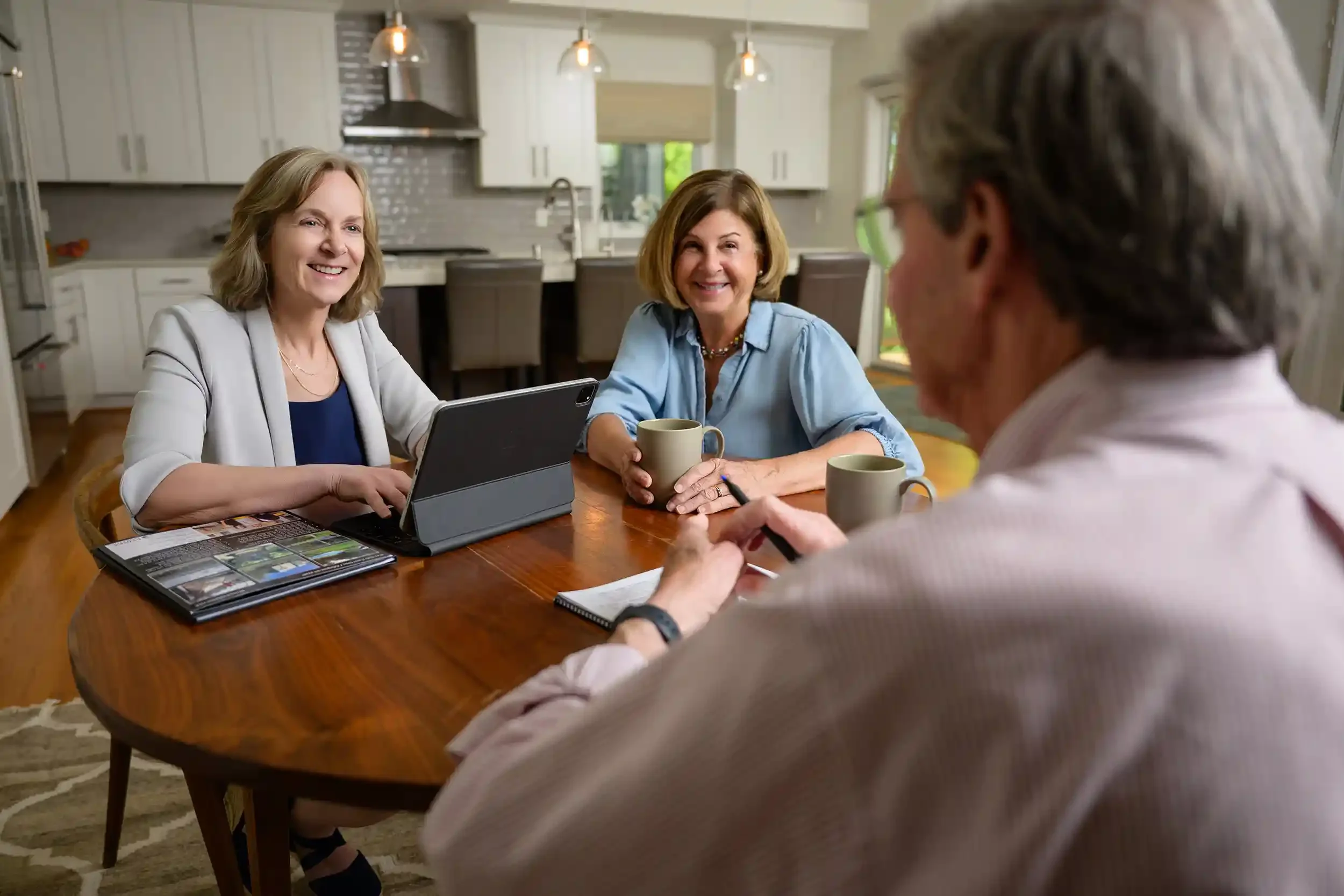 Kathy Rehill and senior downsizing clients sitting at a wooden dining table in a kitchen