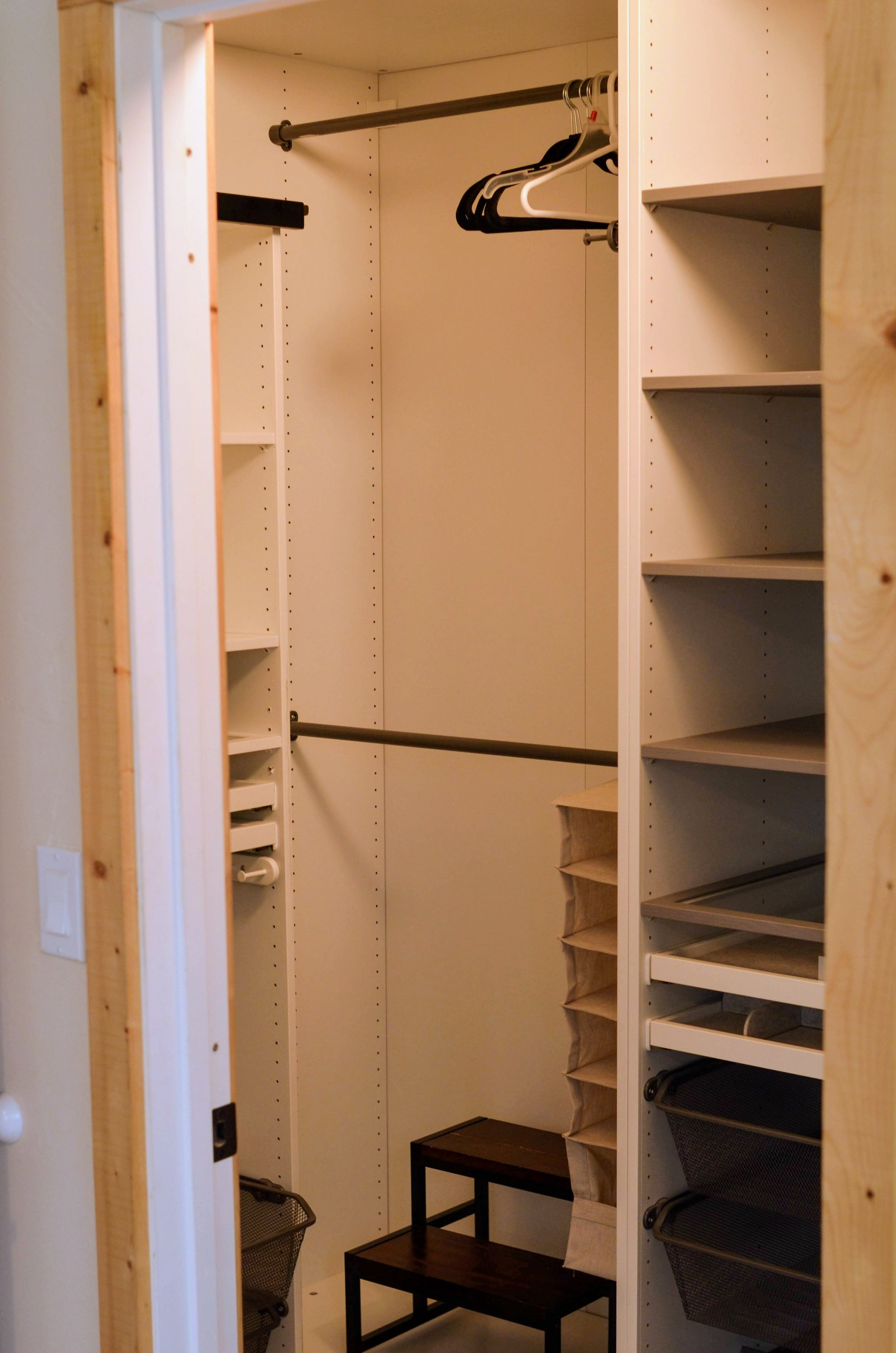Empty closet with built-in shelves, hanging bars, a small black table, and a small cart visible in the bottom left corner.