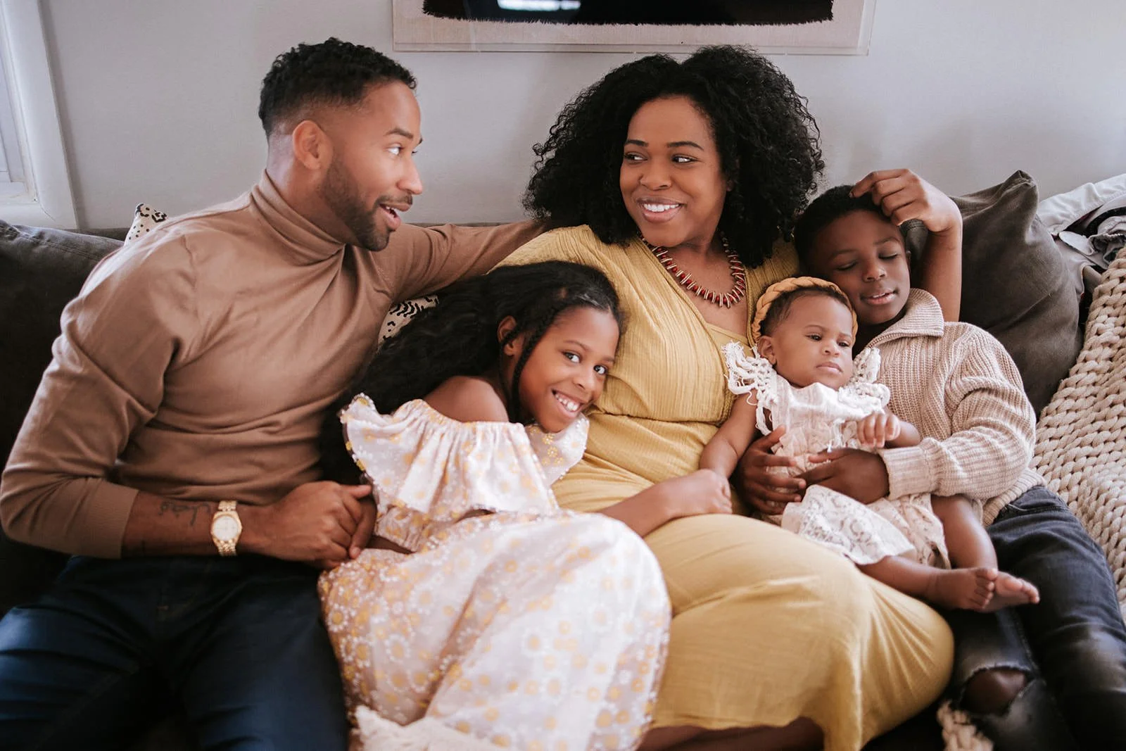 A family of six sitting on a couch smiling and relaxing together.