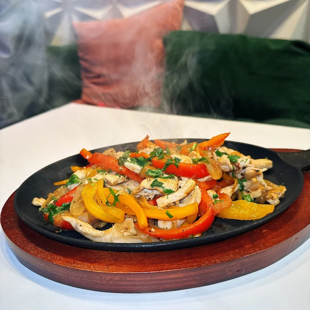 Sizzling chicken stir-fry with colorful bell peppers on a hot cast iron skillet
