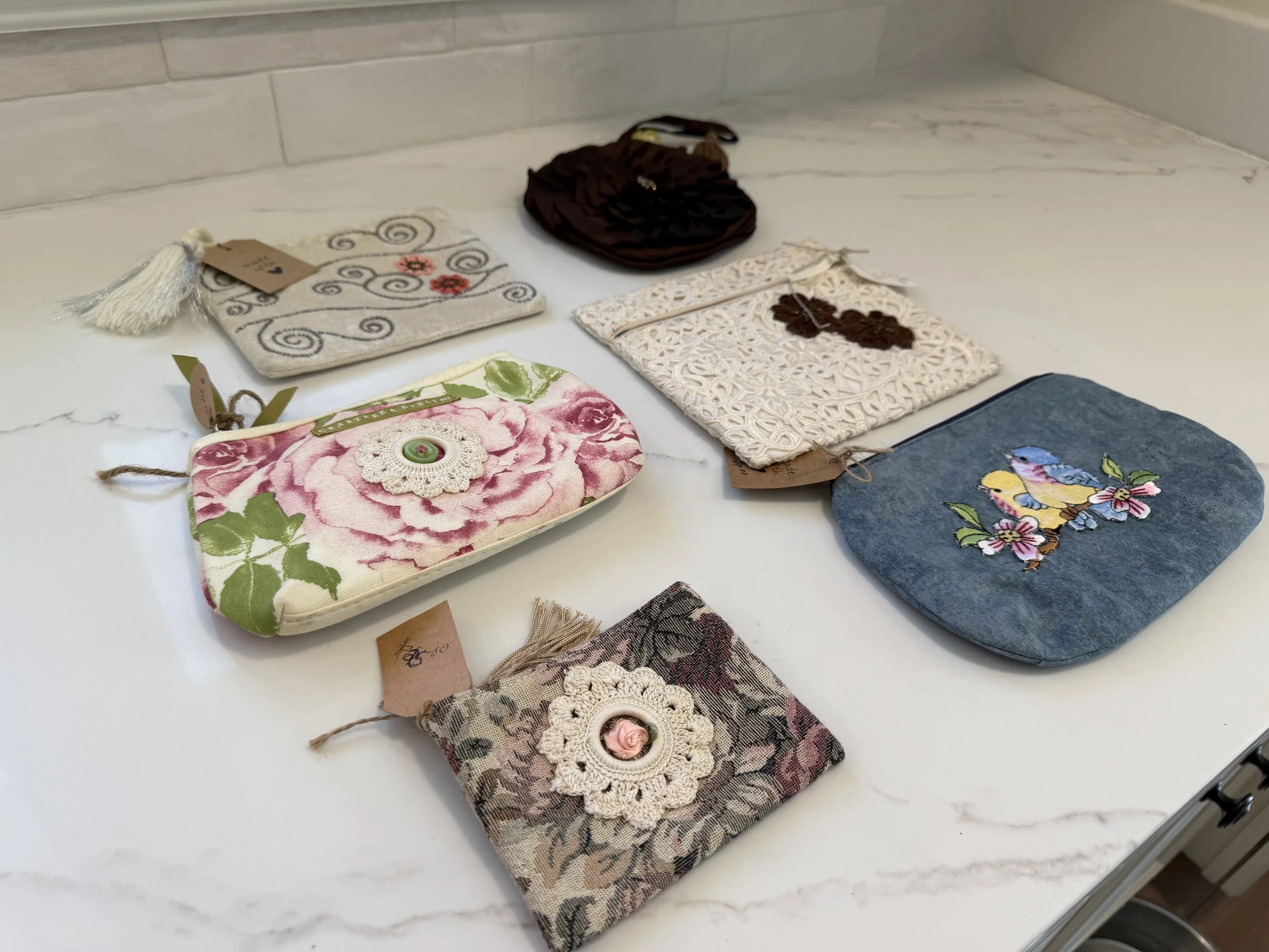 Various small fabric pouches with decorative elements laid out on a white surface.