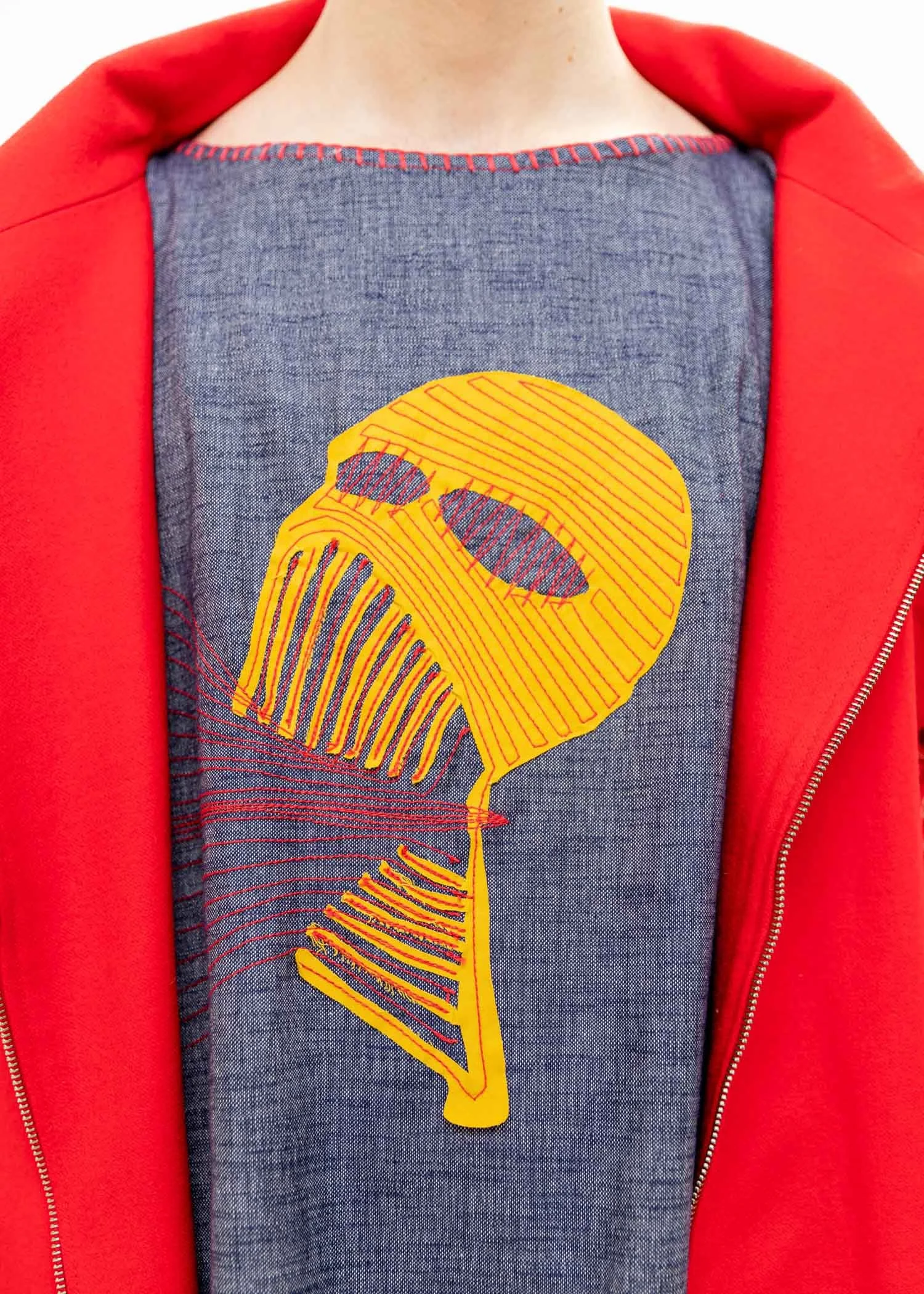 A person wearing a gray t-shirt with a yellow and red outline of a brain graphic, topped with a red jacket open in front.