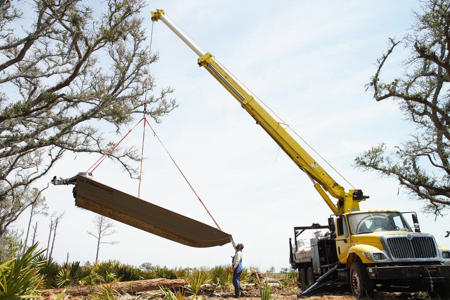 Crane truck lowering boat into marsh on Sapelo Island, GA